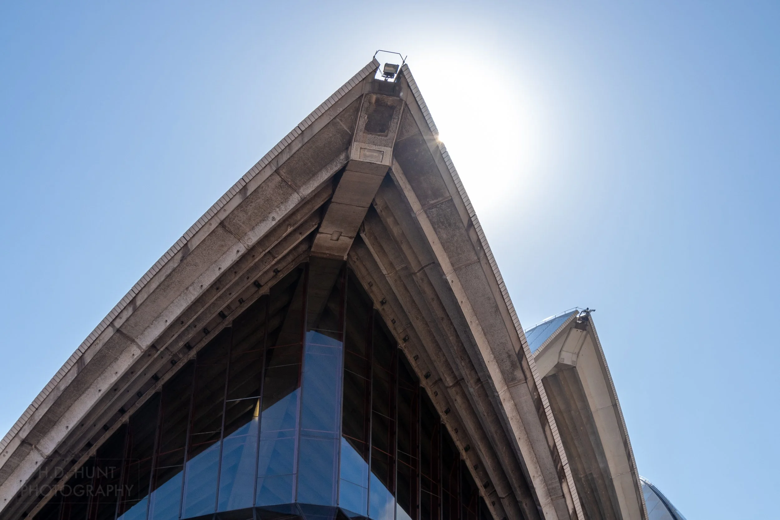 The sun peeks from behind one of the points in the Sydney Opera House roof, Sydney, New South Wales, Australia.