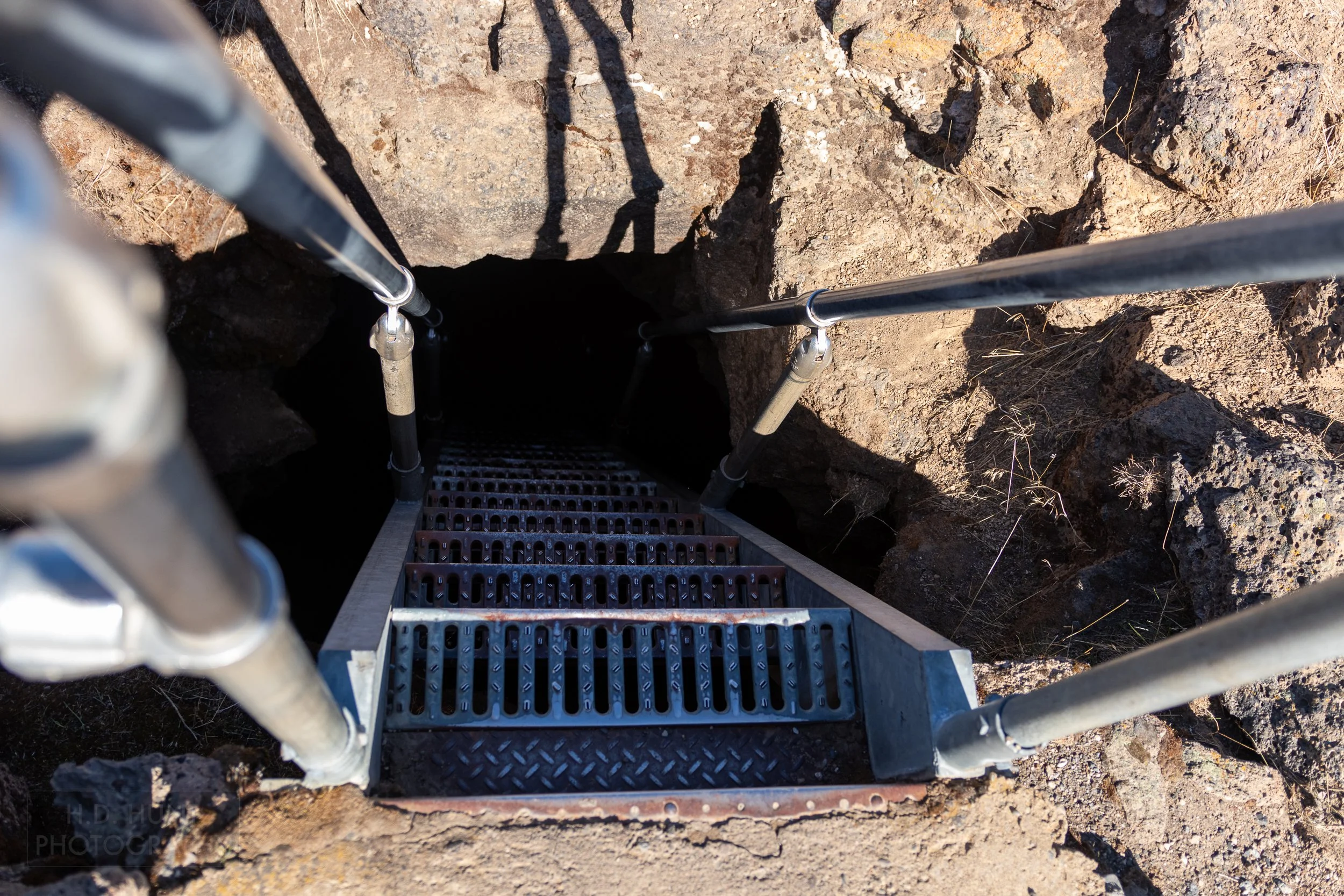 A steep steel staircase leads underground to a lava tube, Lava Beds National Monument, California, United States.