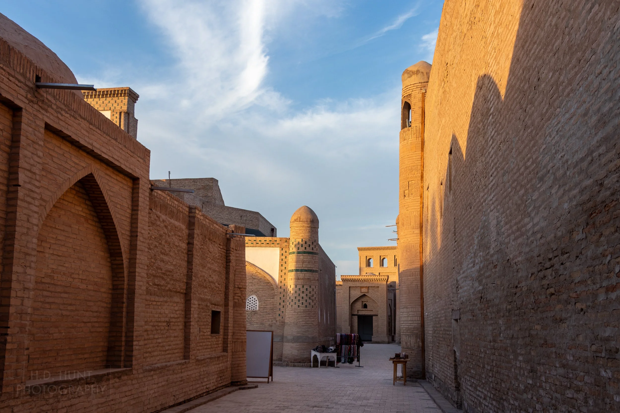 A quiet alleyway with a vendor's wares on a display rack in Khiva, Uzbekistan.