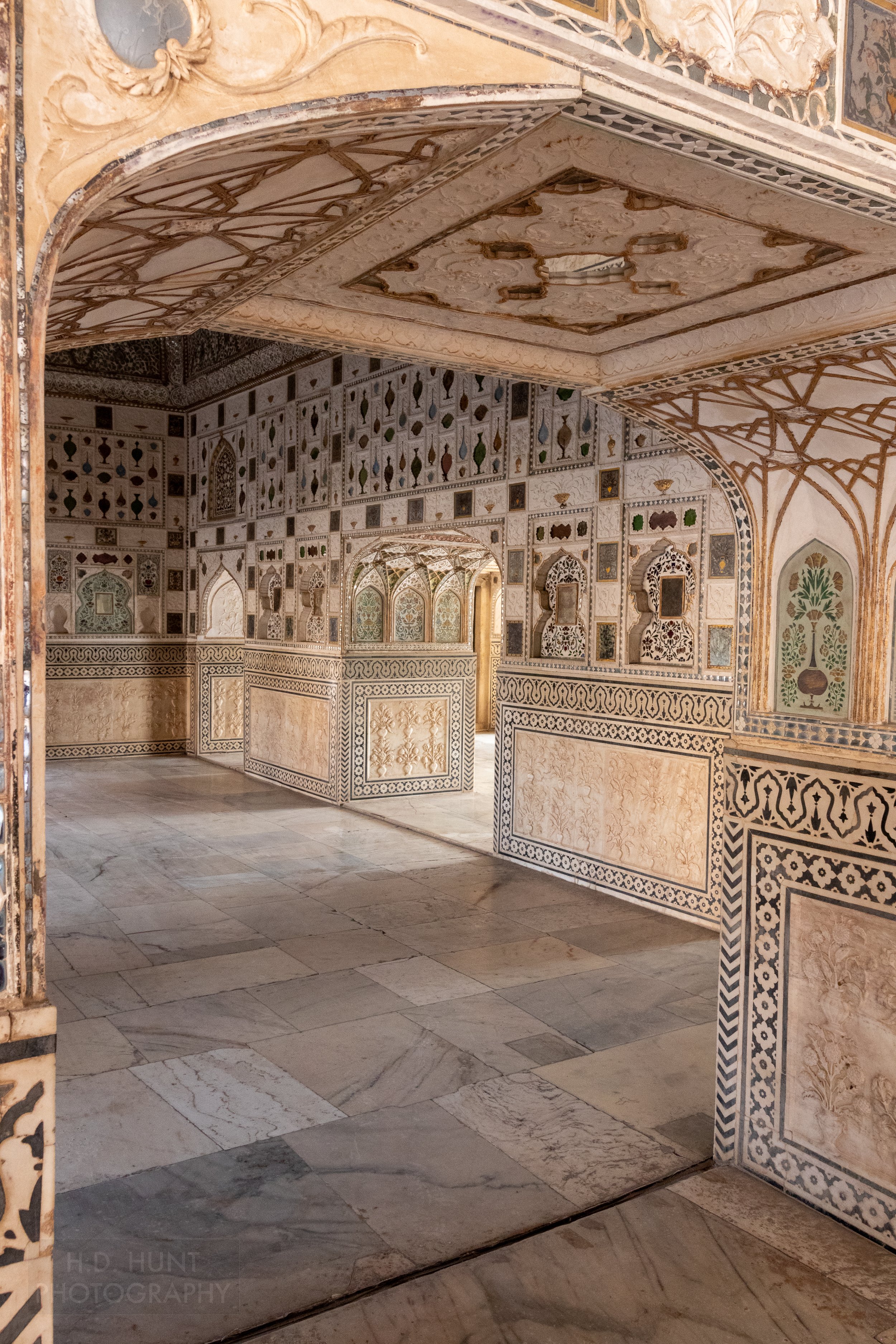 A white-colored wall with intricately carved and tiled features, Amber Fort, Amer, India.