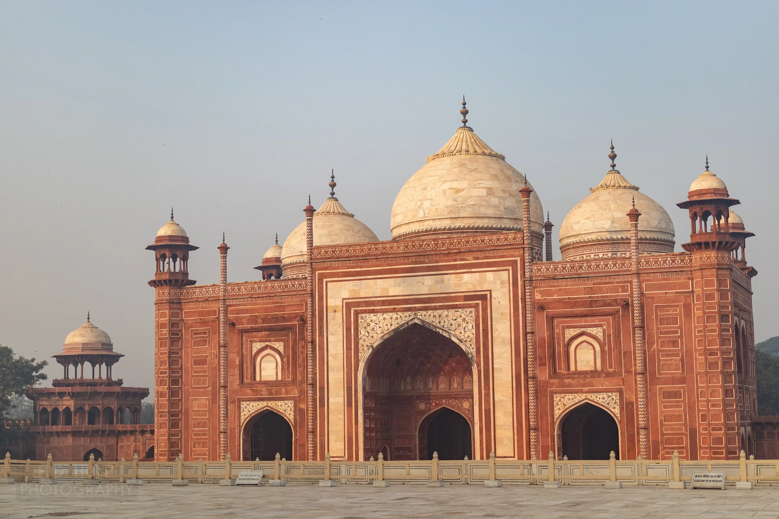 The red and white sandstone Taj Mahal mosque building, featuring three large onion-shaped domes and four corner towers, Agra, India.