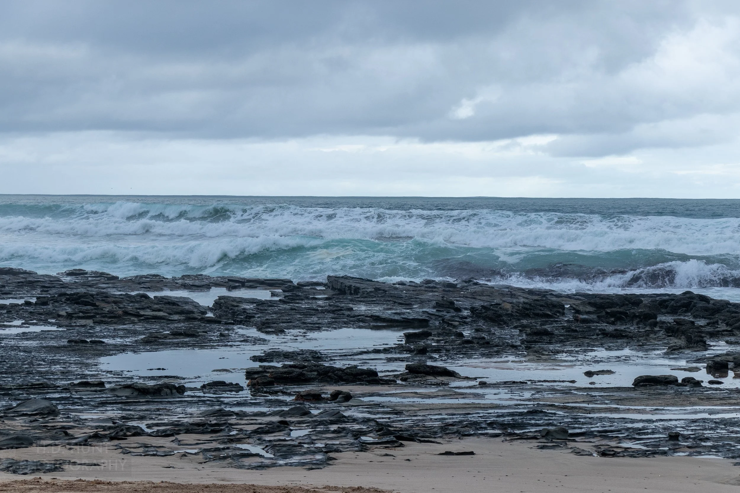 Waves crash into rocks along the beach along The Great Ocean Walk, Victoria, Australia.