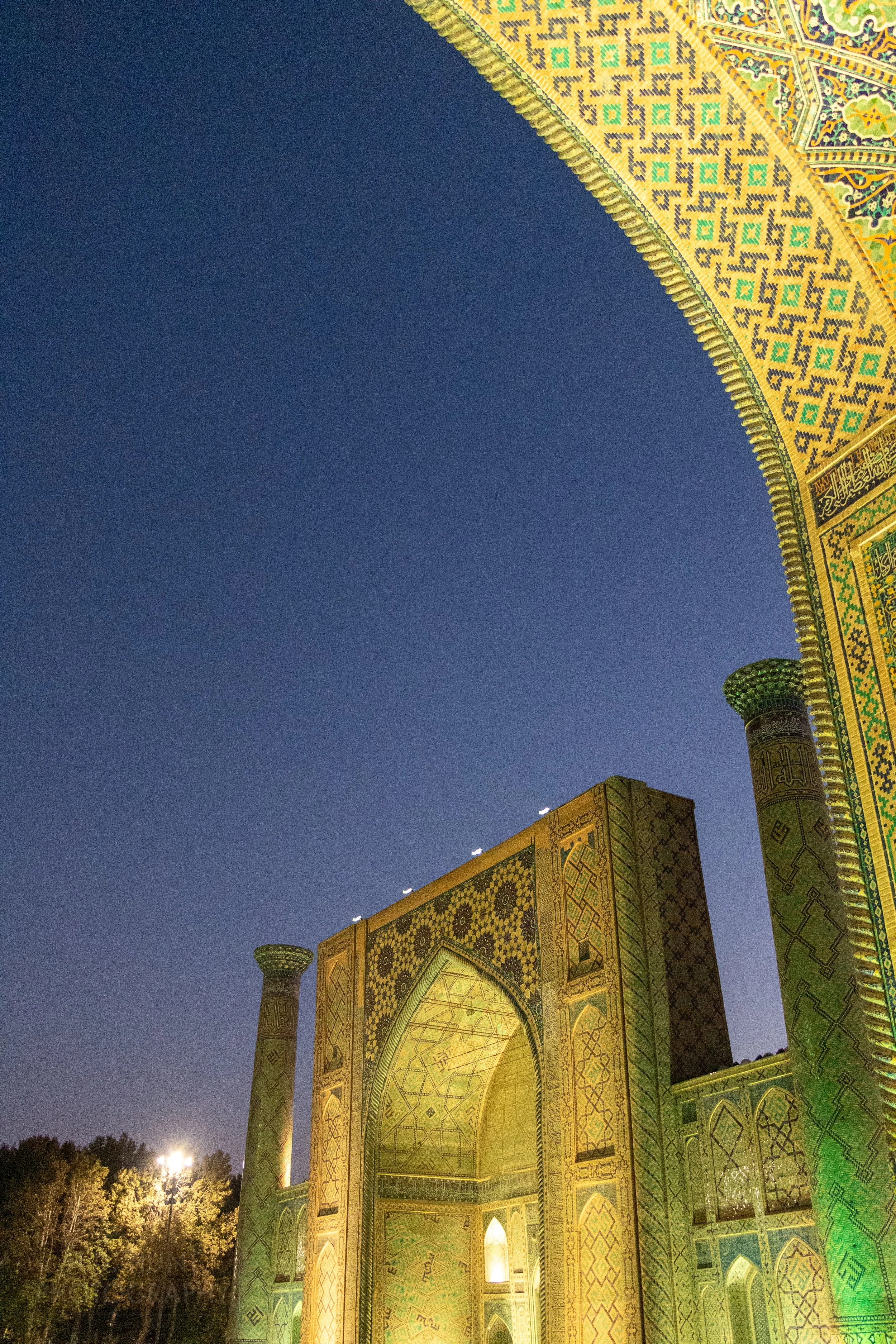 A view of the facade of the Ulugh Beg Madrasa illuminated by flood lights at the Registan, Samarkand, Uzbekistan.