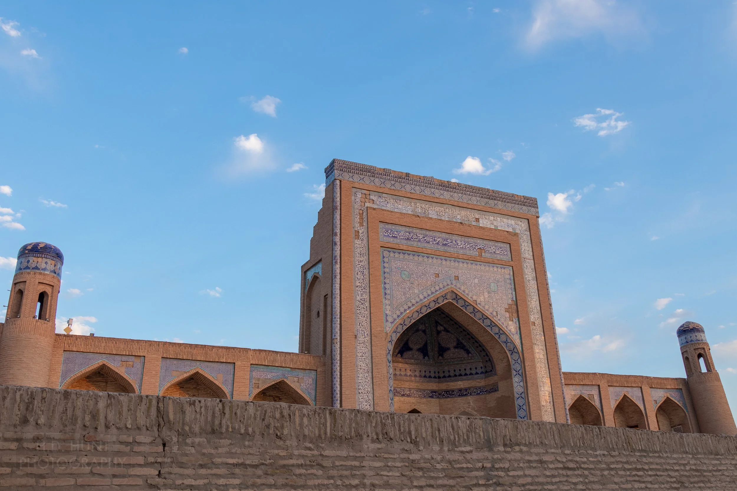 The tiled entrance of the Kuhna Ark stands flanked by shorter walls with round towers, Khiva, Uzbekistan.