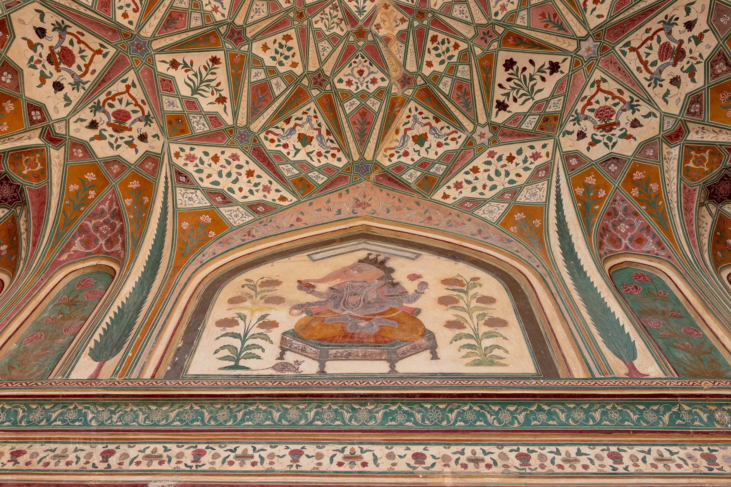 A painting of a religious figure and a ceiling of intricate red and white tiles is seen within Amber Fort, Amer, India.