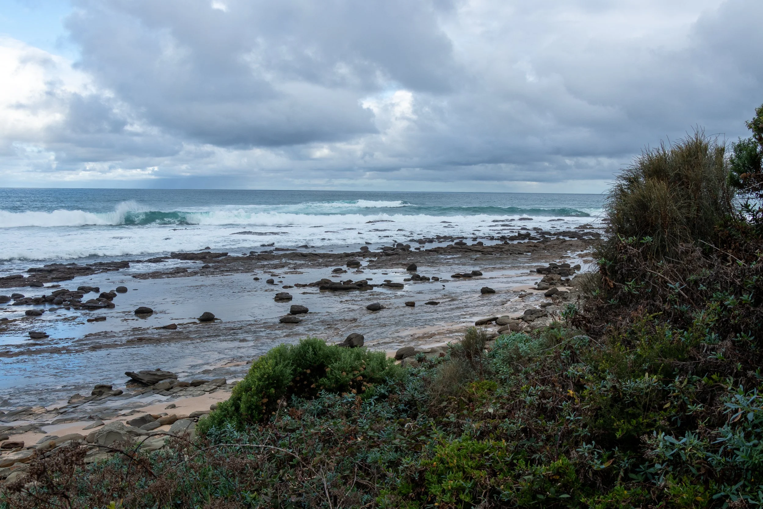 Waves crash into rocks along the beach along The Great Ocean Walk, Victoria, Australia.
