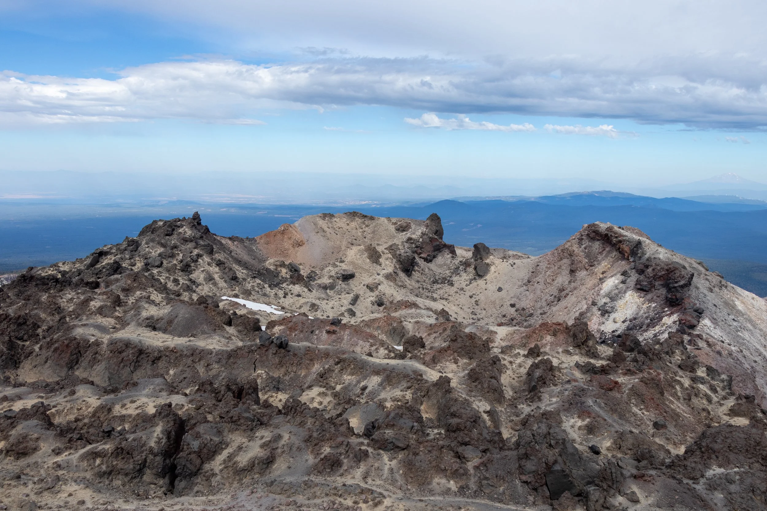 Mount Shasta is seen in the far distance beyond the rocky peak of Lassen Peak, Lassen Volcanic National Park, California, United States.