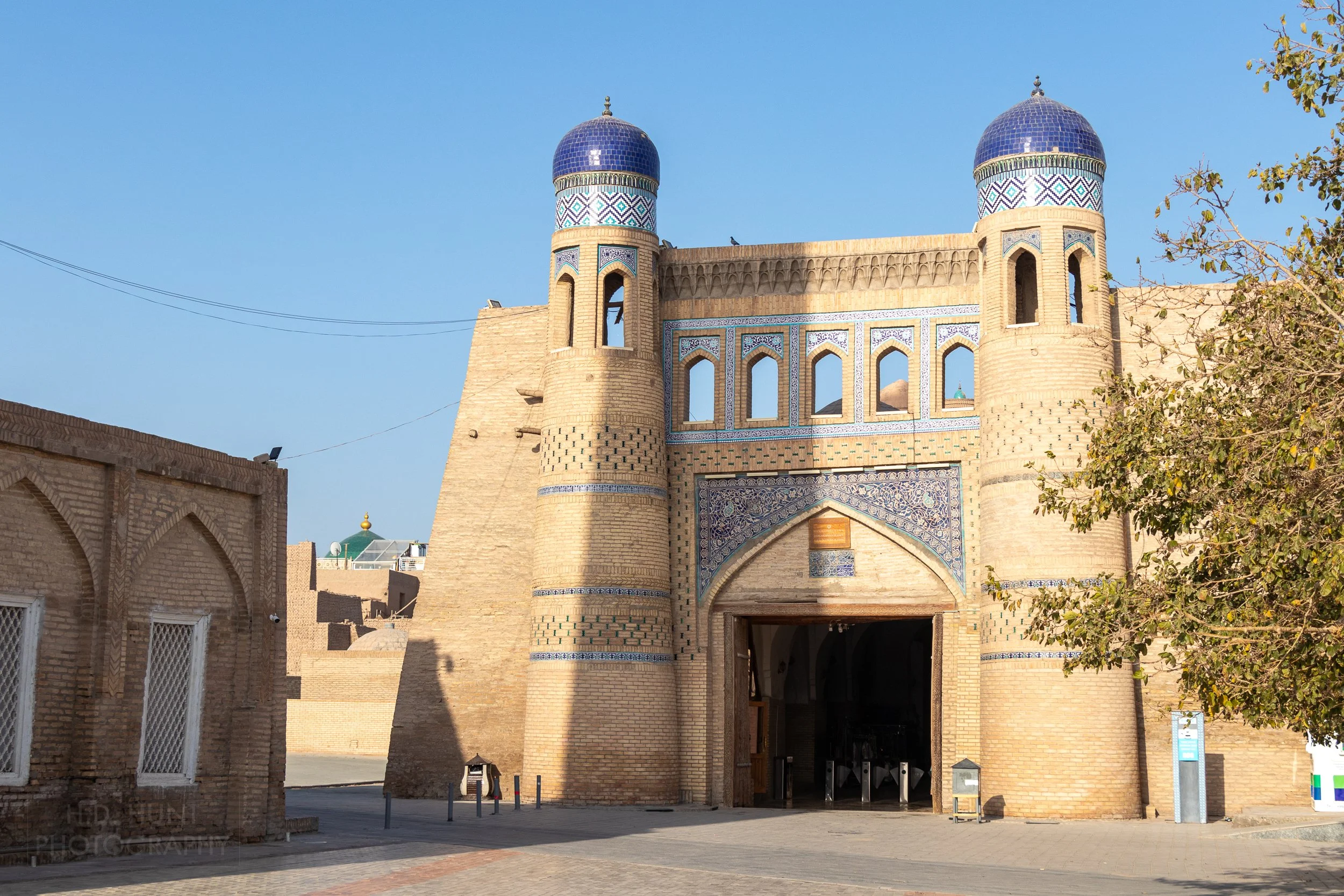 The square opening of the Polvon Gate is flanked by two taller blue tile-topped towers, Khiva, Uzbekistan.