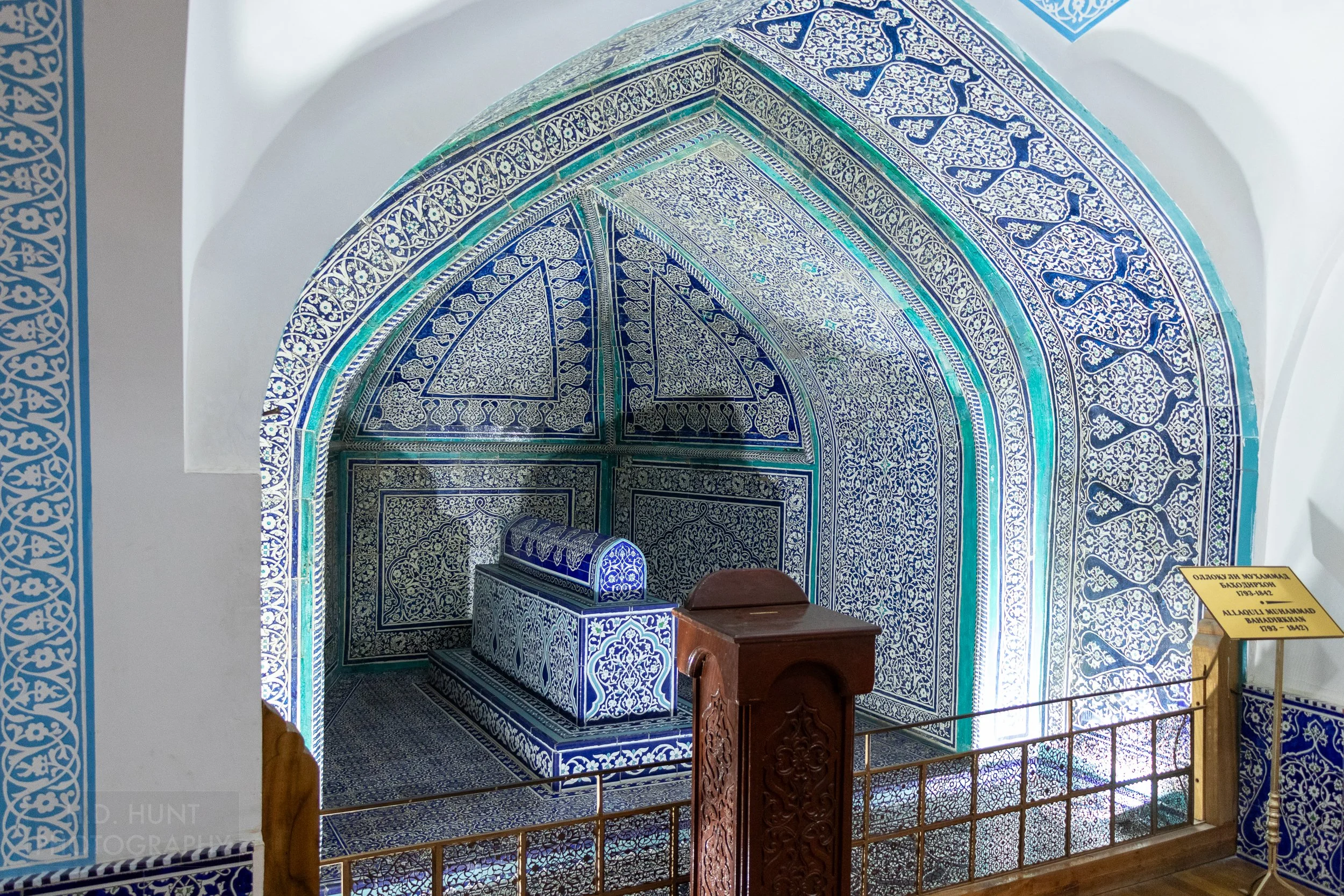 An ornate sarcophagus covered in bright blue and white tiles is seen in the Pahlavan Mahmoud Mausoleum, Khiva, Uzbekistan.