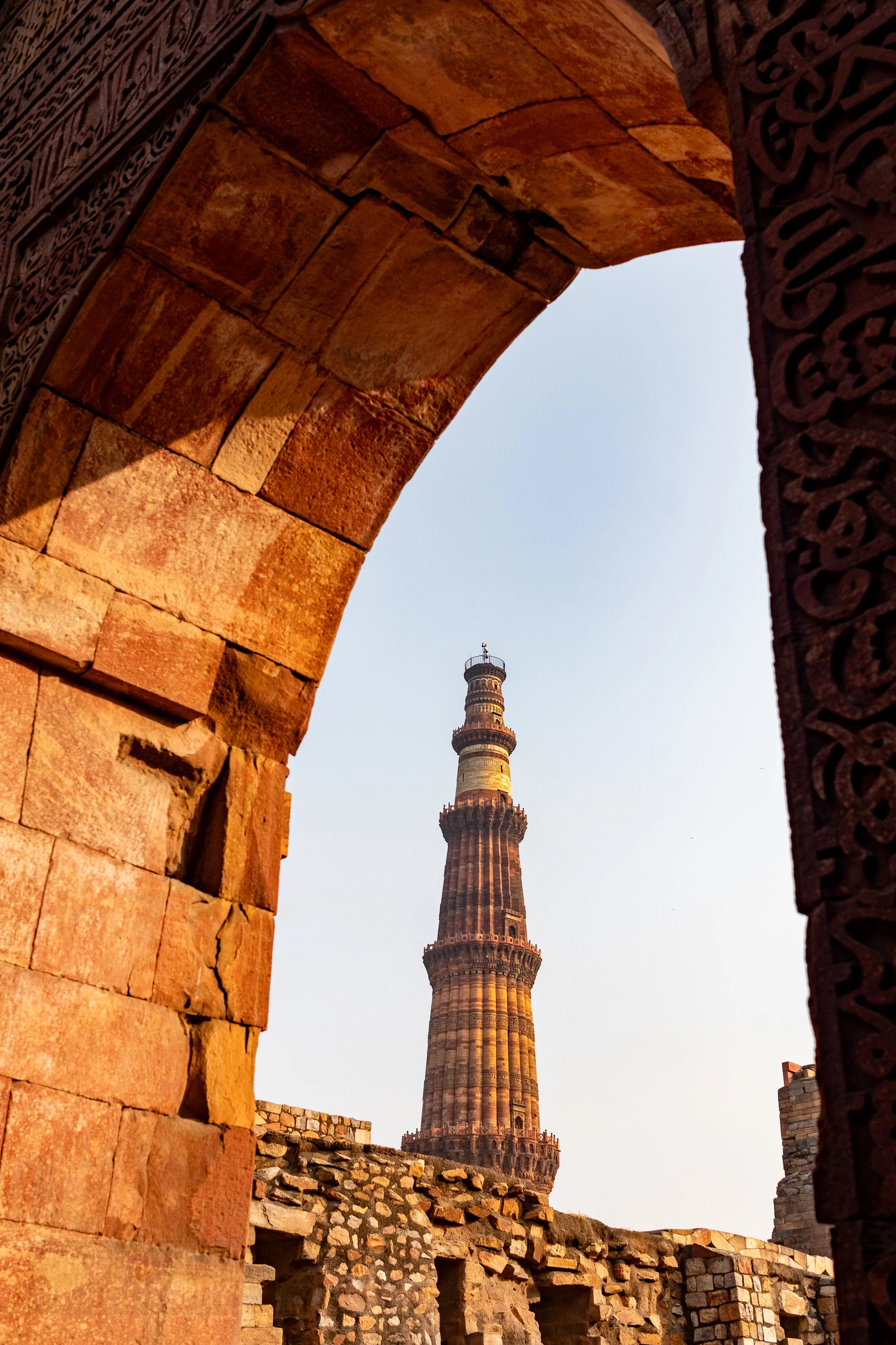 The Qutub Minar minaret is seen through a stone archway, Delhi, India.