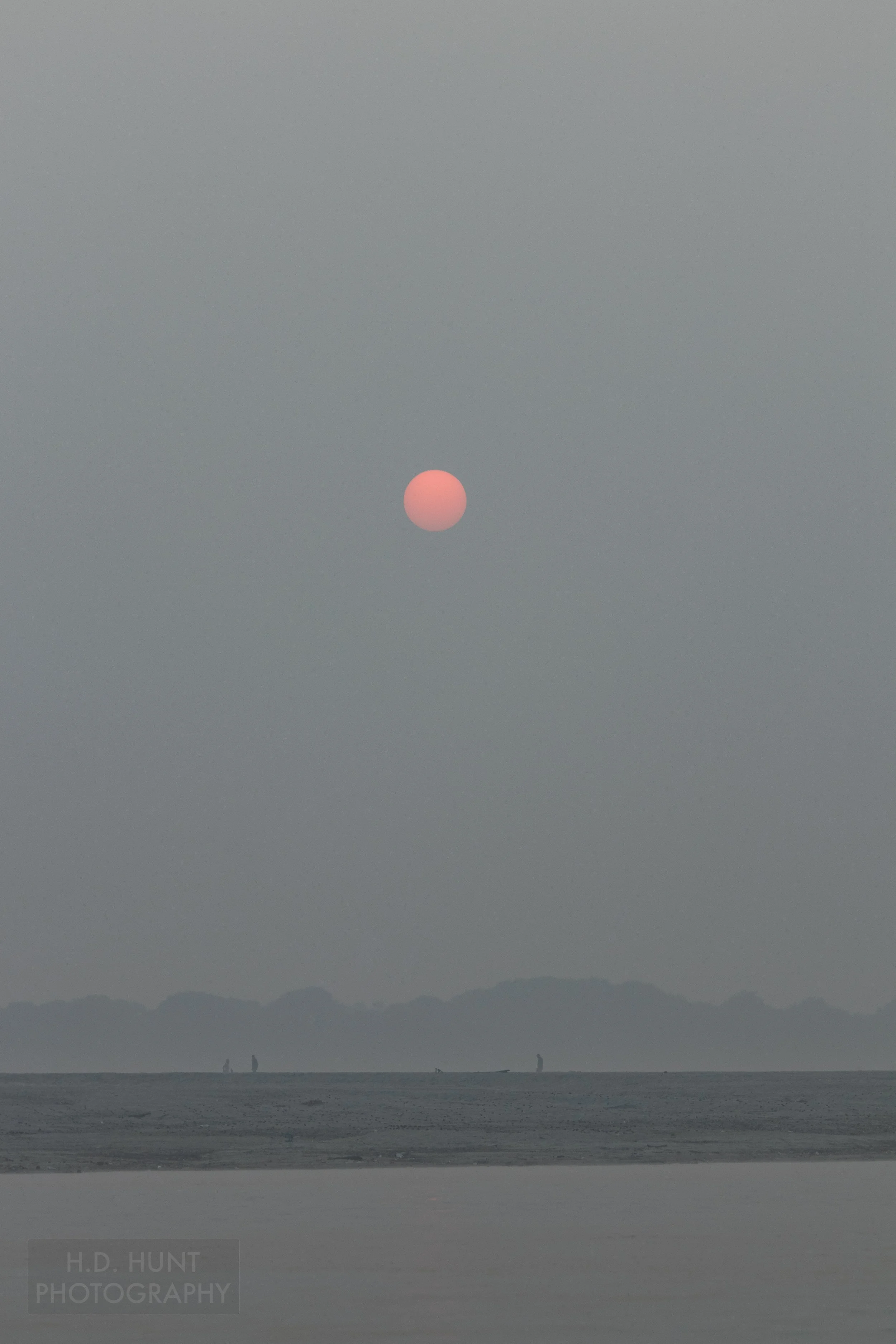 The sun is seen through thick haze above the Ganges River, Varanasi, India.