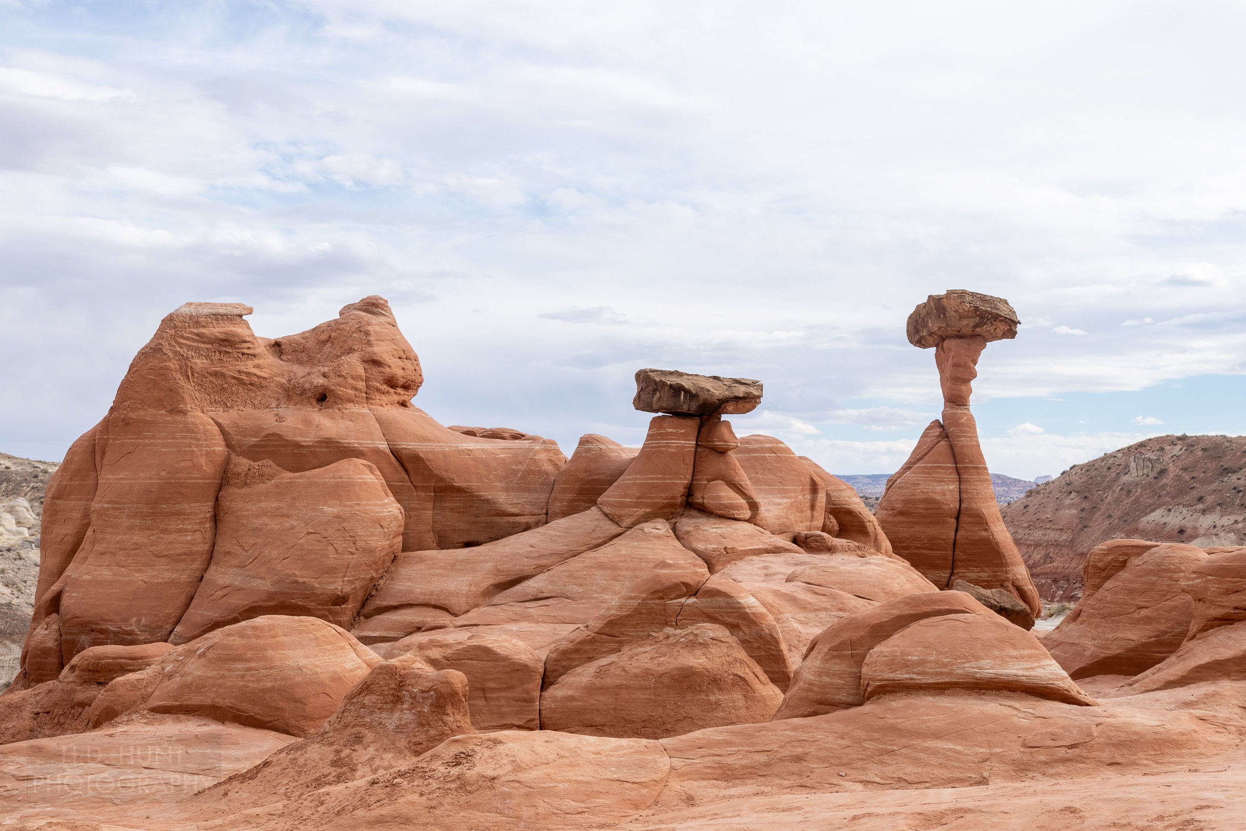 Two large red sandstone column of rock with flat boulders balanced on top of the column sit above a white rock valley, Toadstool Hoodoos, Grand Staircase - Escalante National Monument, Utah, United States.