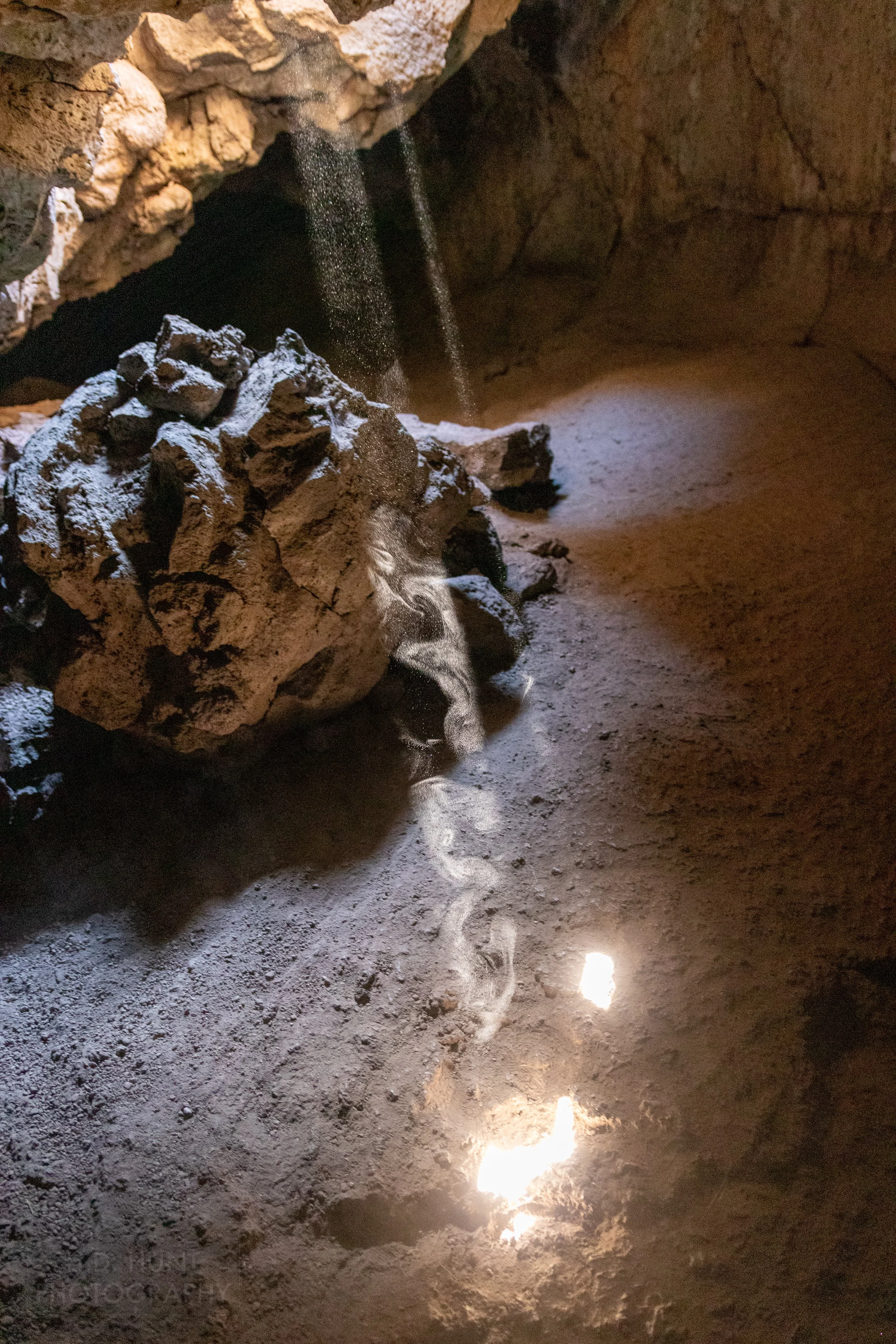 Two beams of light penetrate the ceiling of a lava tube striking the tunnel's floor, Lava Beds National Monument, California, United States.