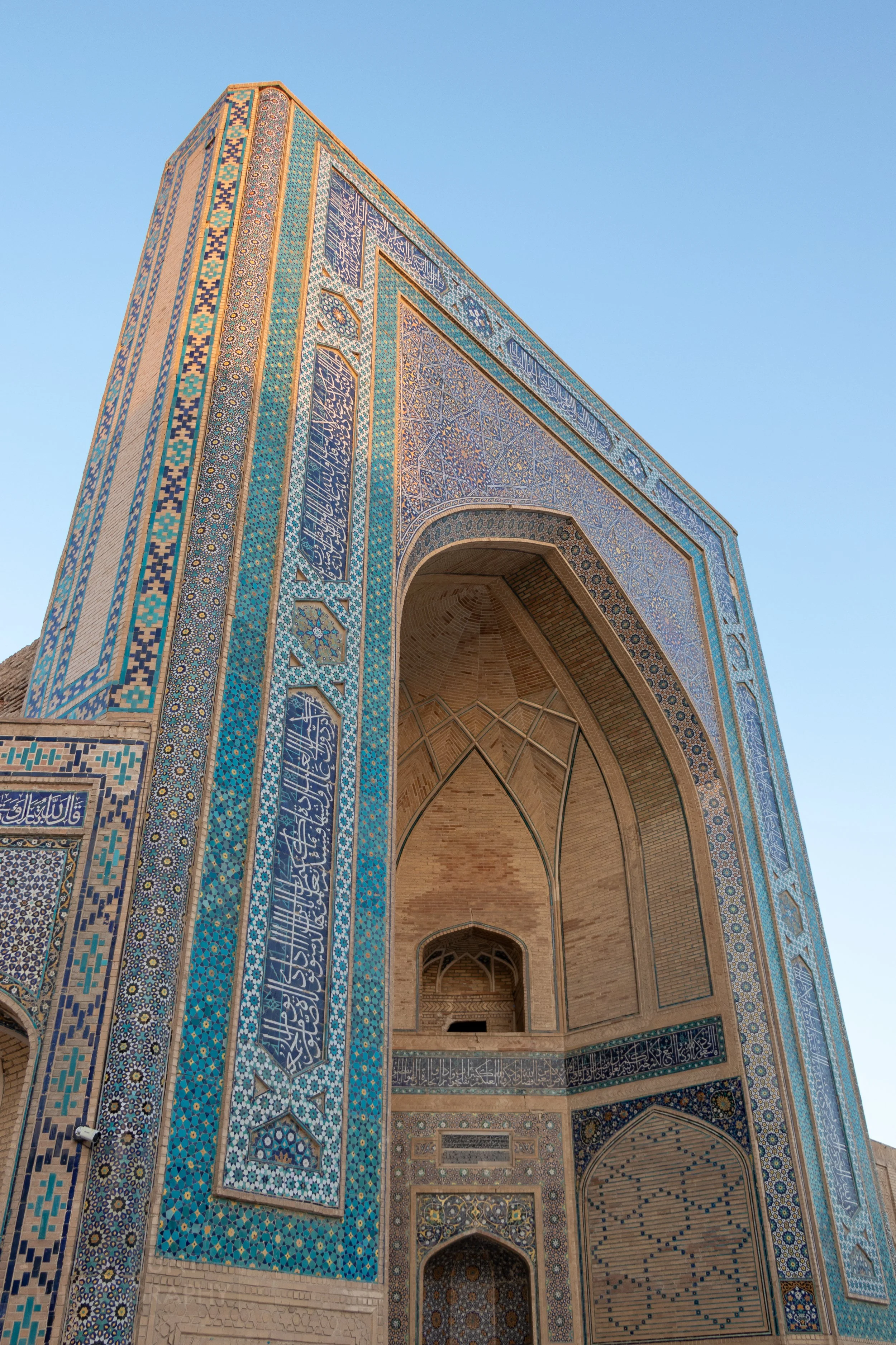 The upper left corner of the intricately-tiled facade of Kalan Mosque is lit by the sunrise in Bukhara, Uzbekistan.