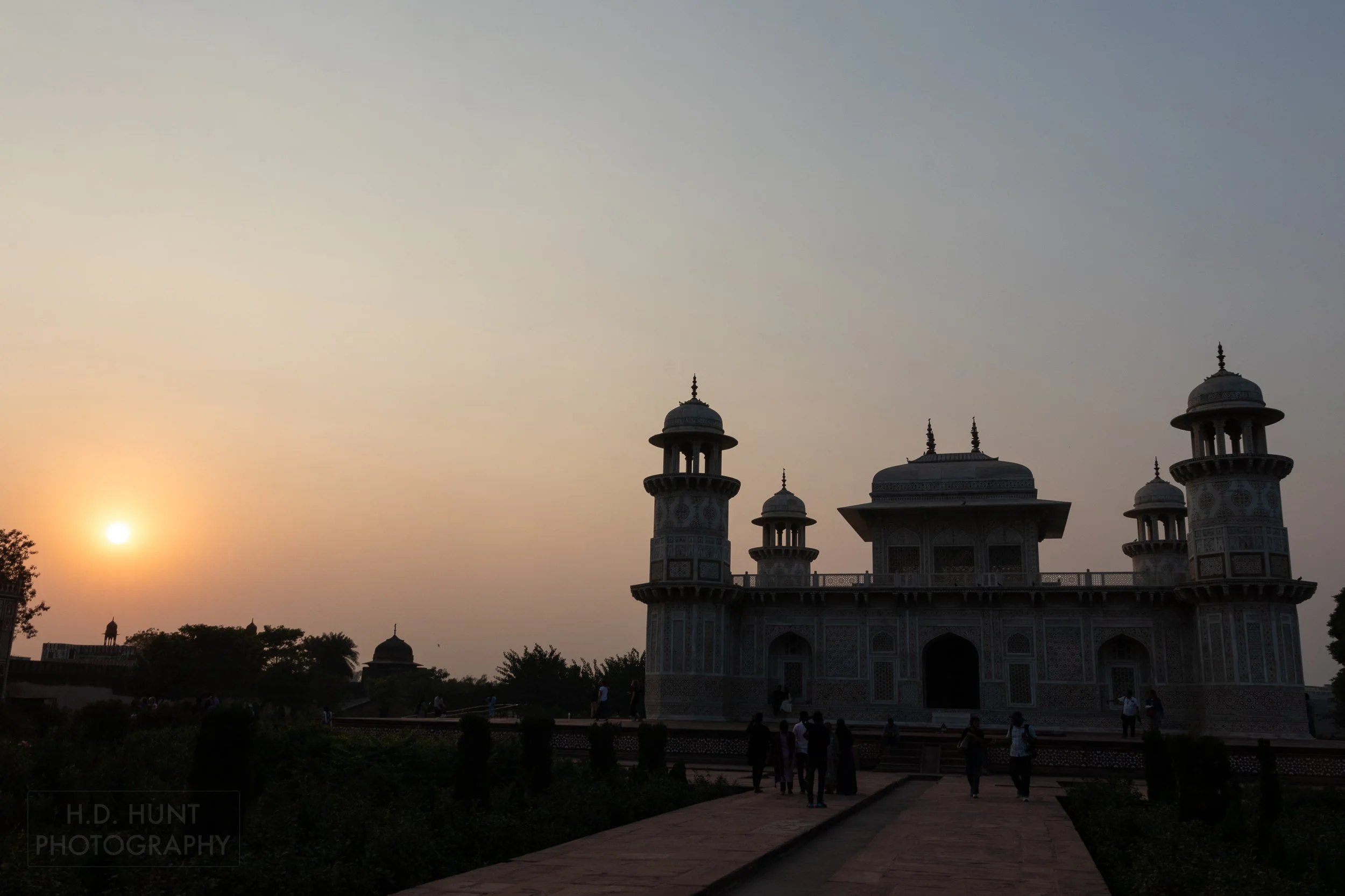 The sun begins to set behind a silhouetted Tomb of I’timad-ud-Daulah, Agra, India.