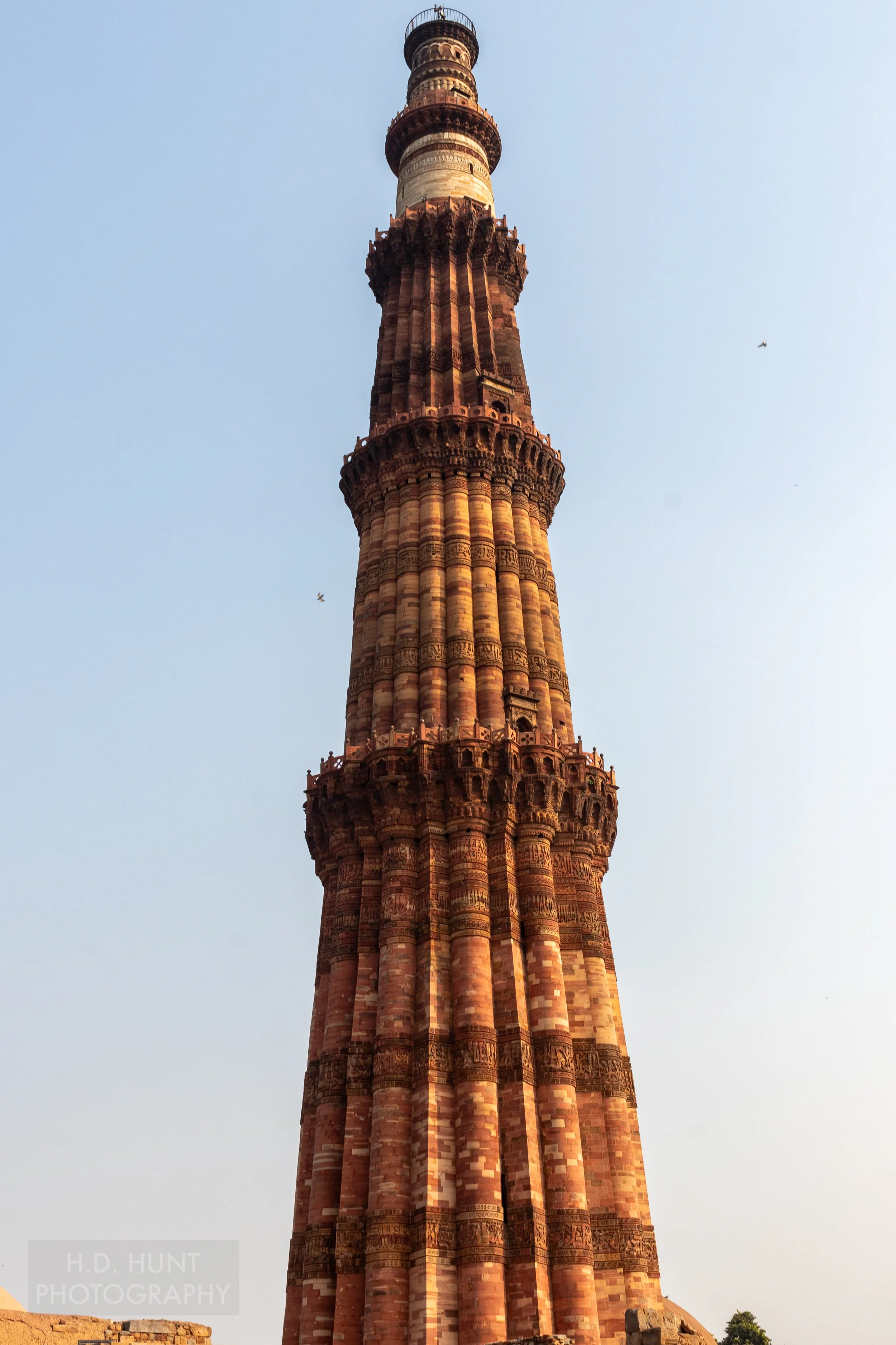 The tan and brown Qutub Minar minaret rises above Delhi, India.