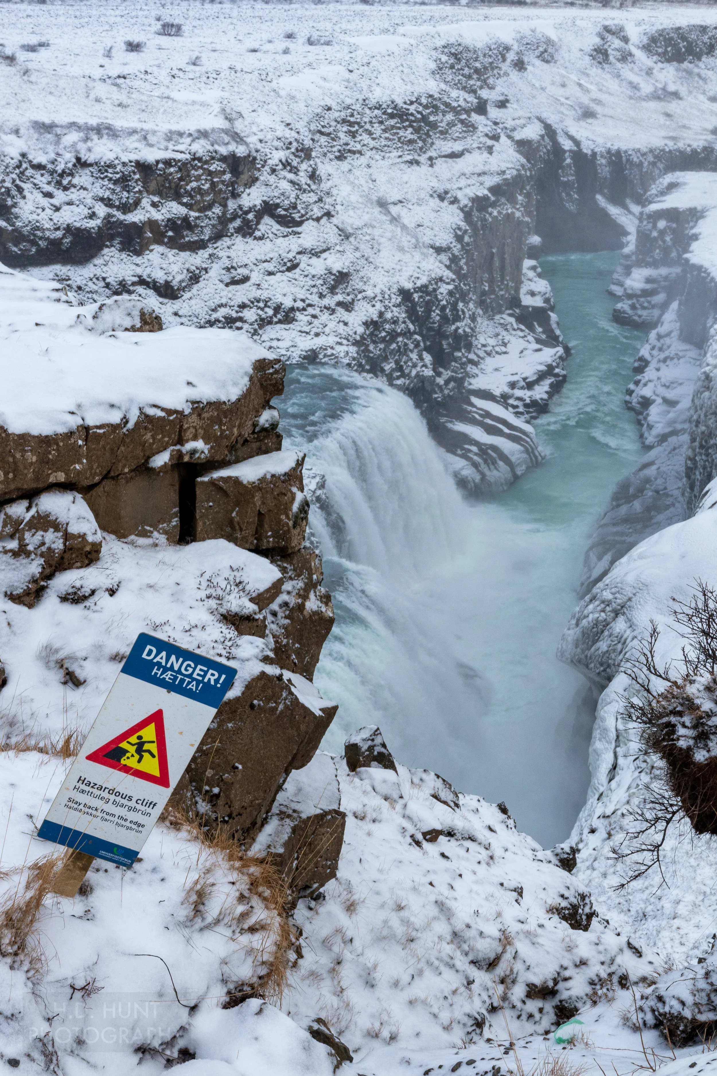 A warning sign denotes a sharp drop-off to a large waterfall, Gullfoss, in Iceland.