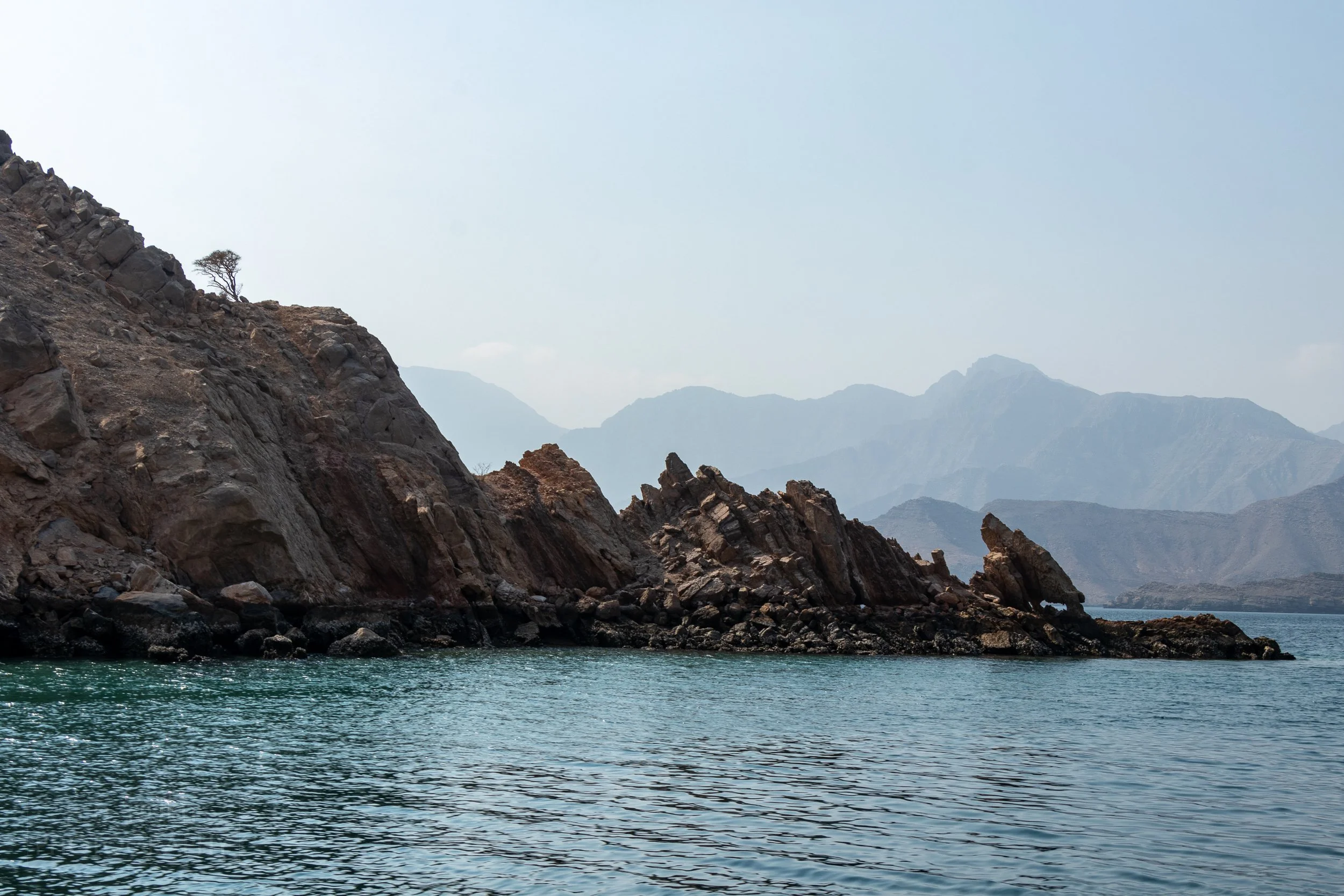 Jagged cliffs poke above the waterline off the Musandam Peninsula, Oman.