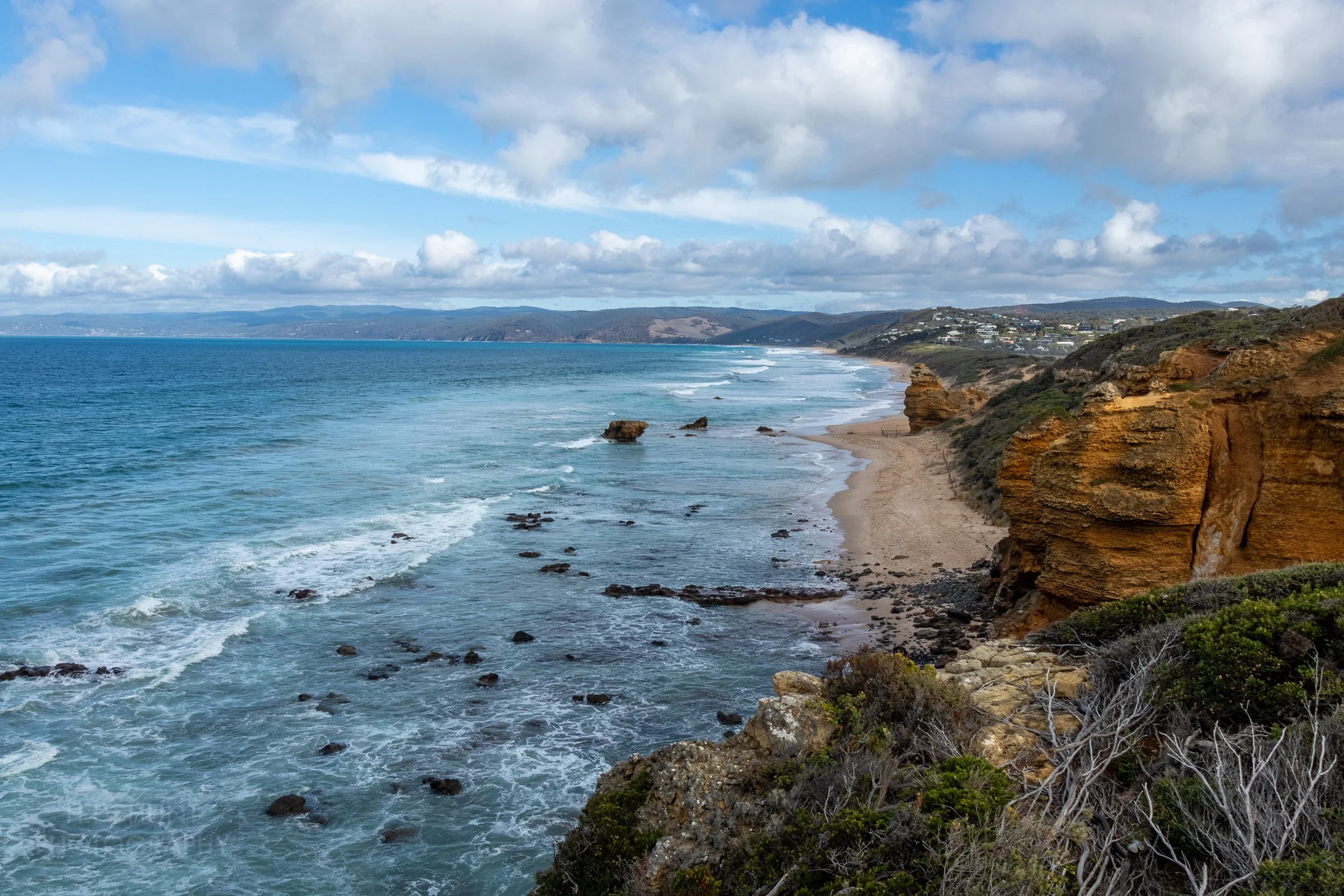 The blue waters of Bass Strait meet the brown and orange cliffs of Aireys Inlet, Victoria, Australia.