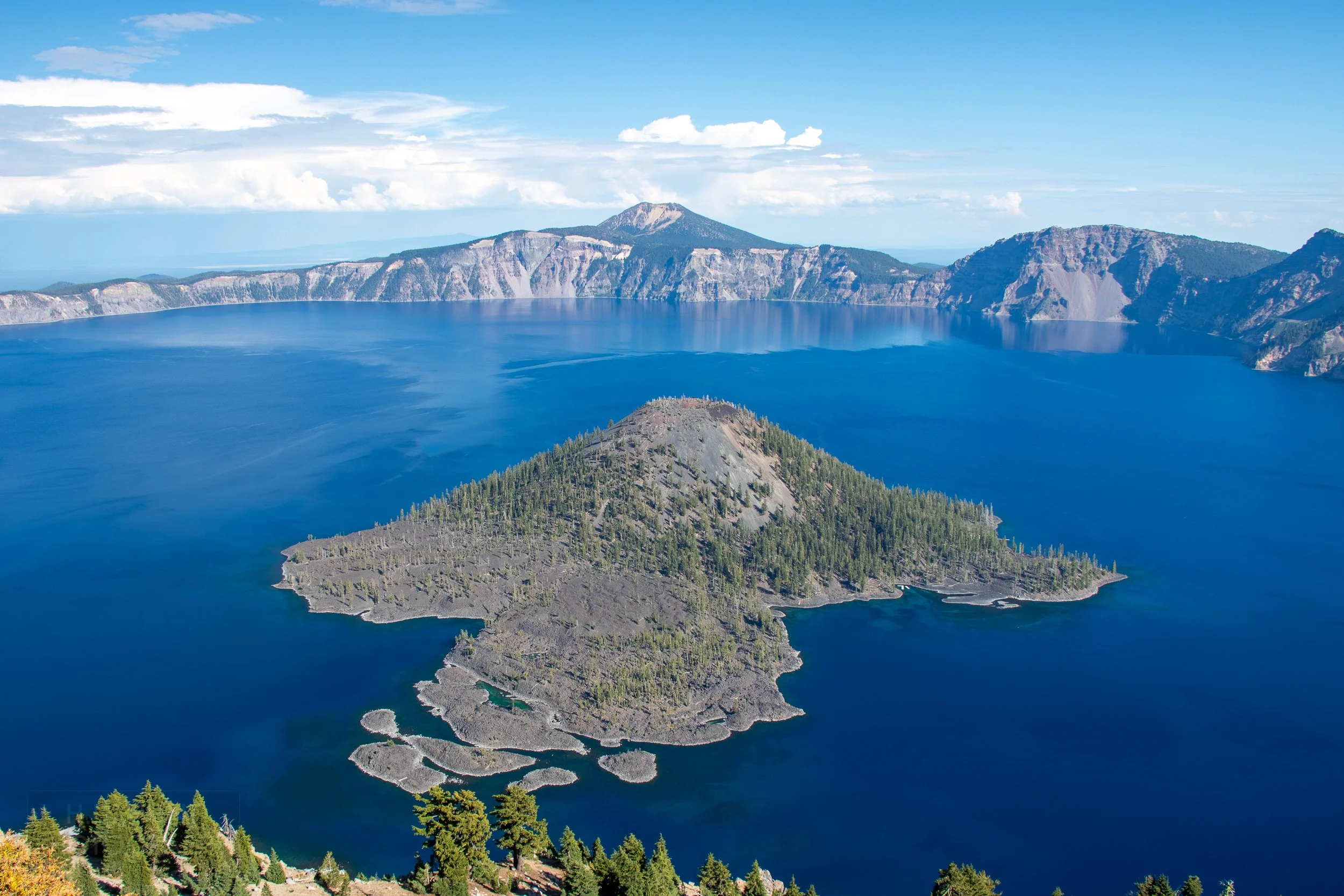 A view of the blue waters of Crater Lake with Wizard Island featured prominently in the foreground, Crater Lake National Park, Oregon, United States.