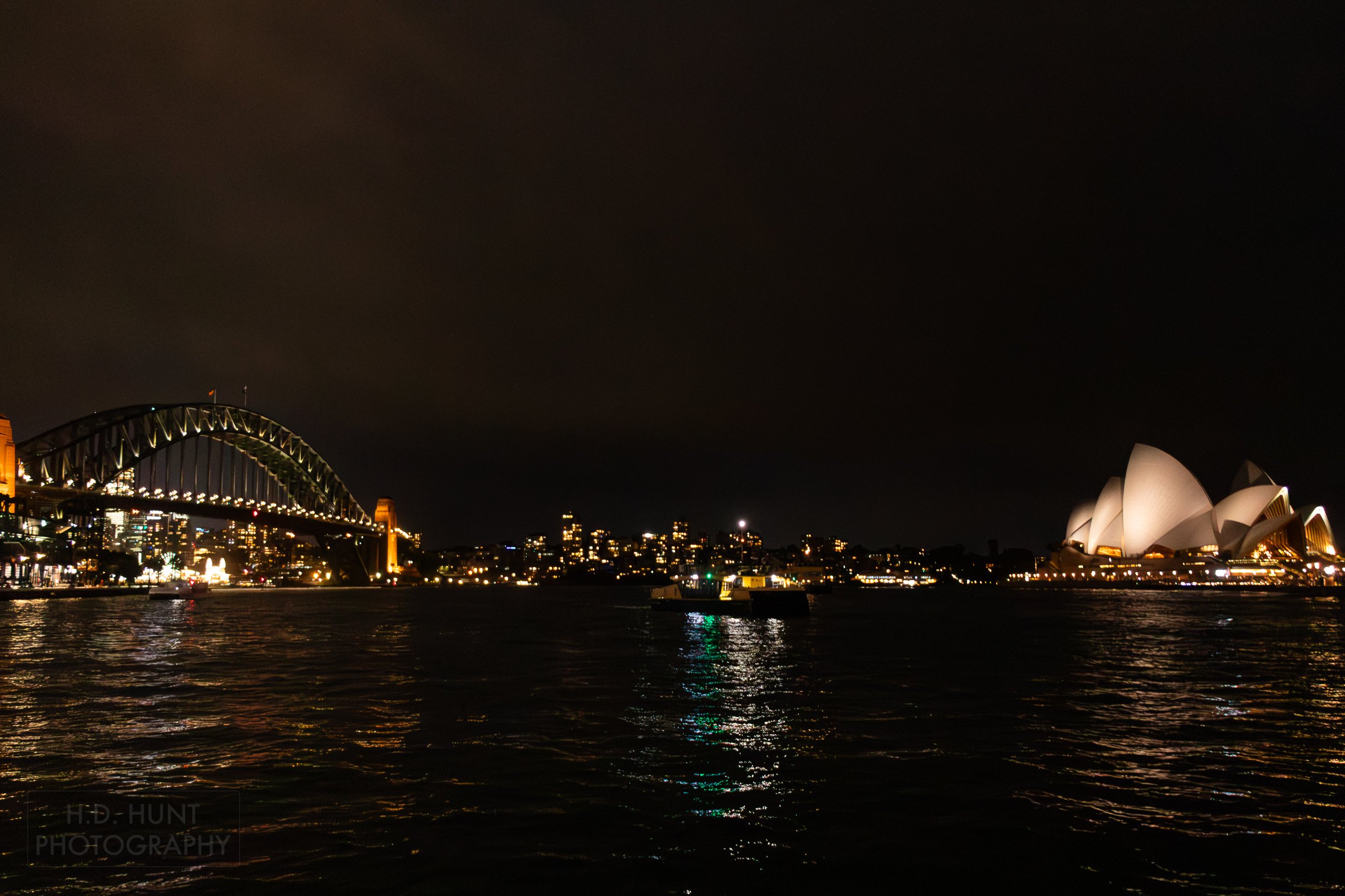 The Sydney Harbour Bridge and the Sydney Opera House are seen at night from a boat in Circular Quay, Sydney, Australia.