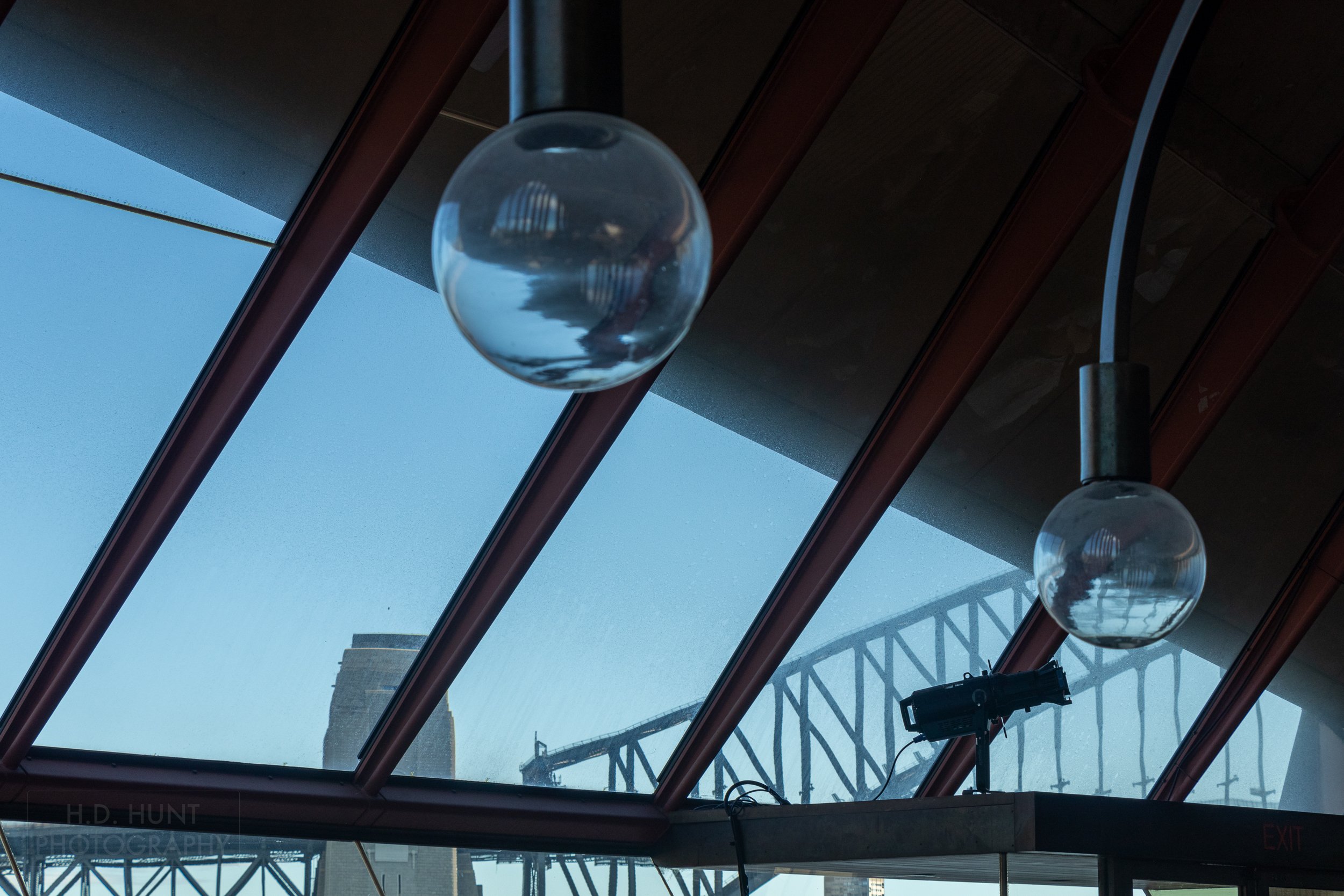 Spherical lightbulbs are seen hanging from the Sydney Opera House roof while the Sydney Harbour Bridge is seen in the background, Sydney, New South Wales, Australia.