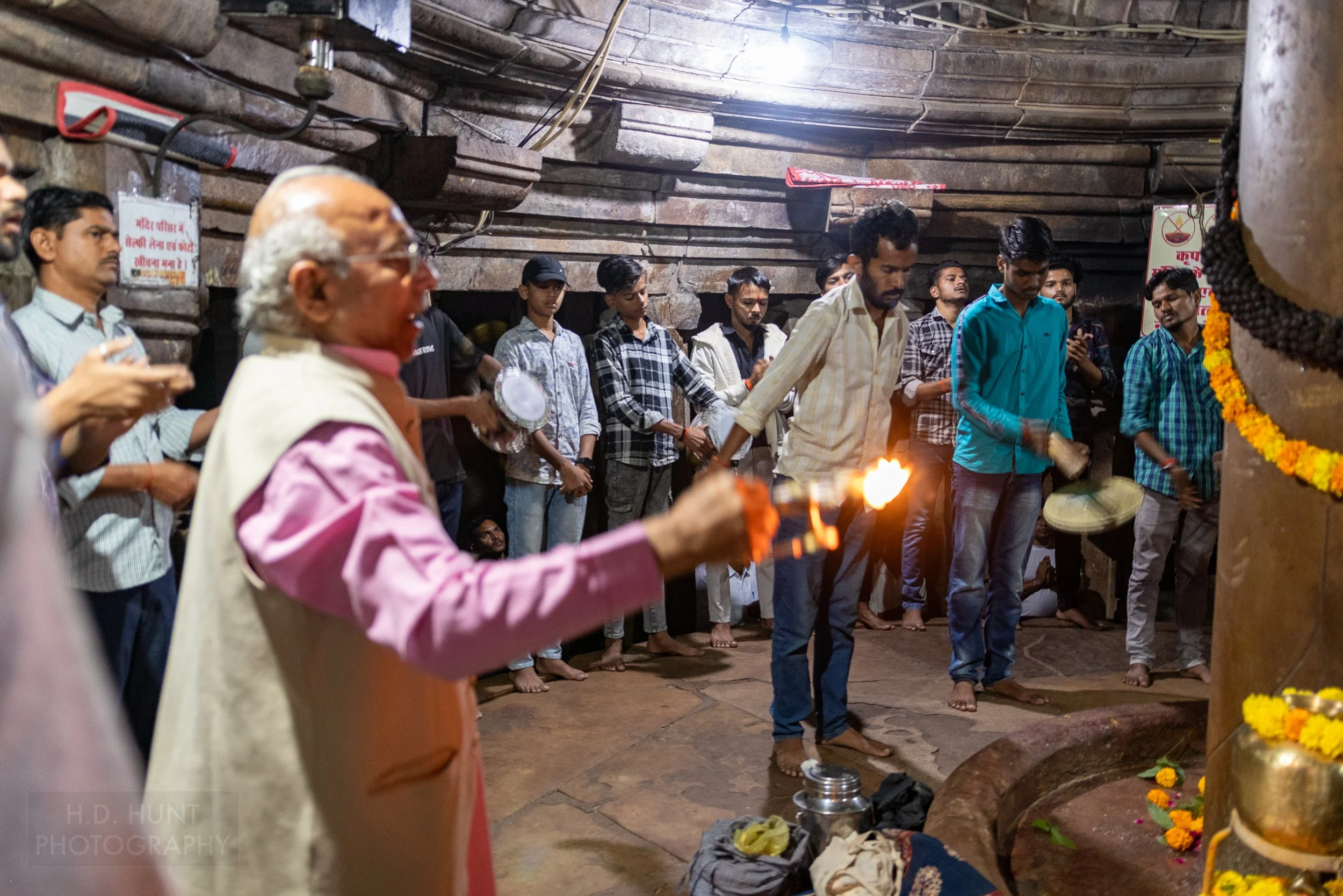 A man holds a lighted oil lamp during a religious ceremony in the stone interior of Matangeshvara Temple, Khajuraho, India.