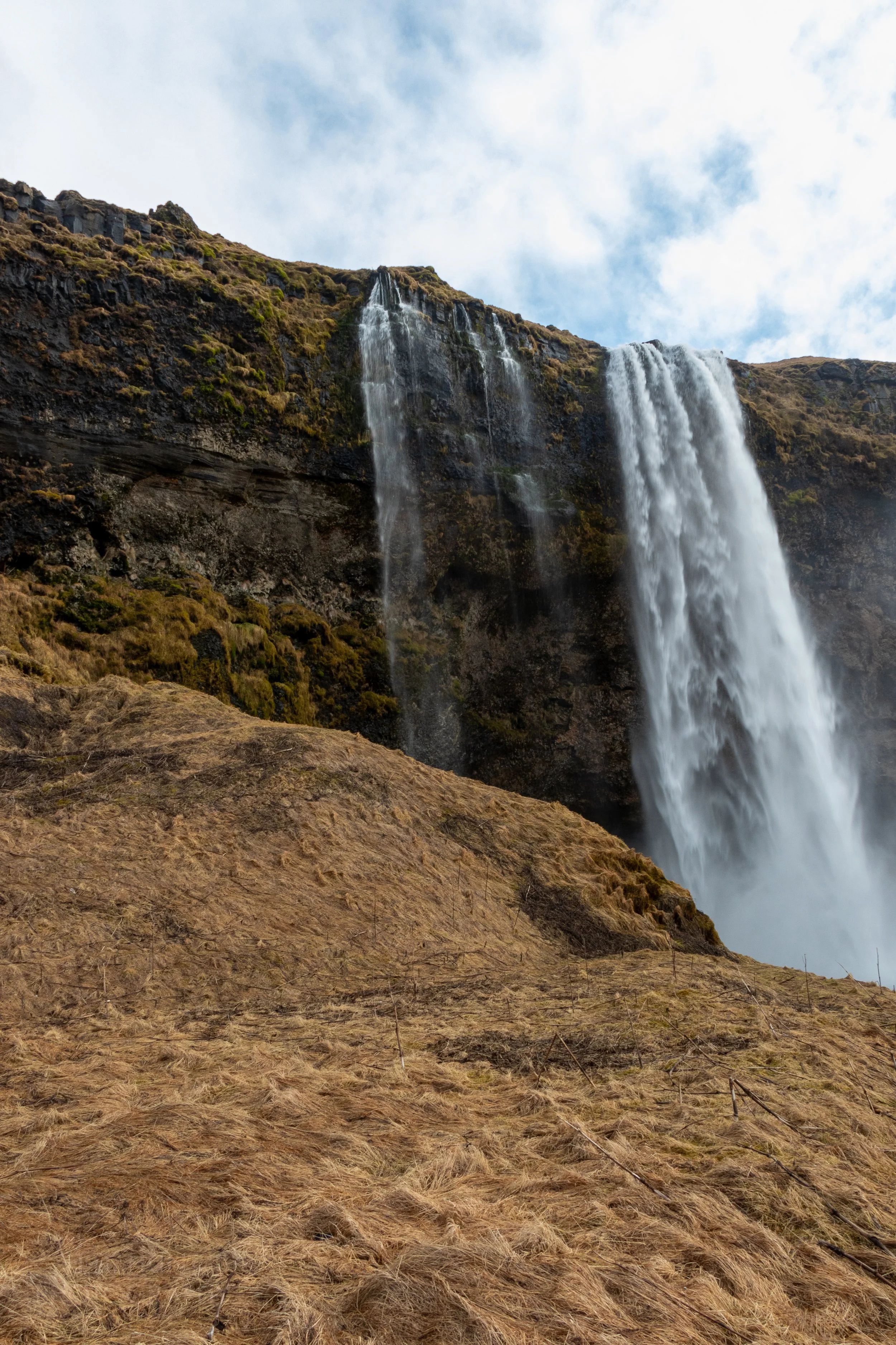 Water spills over a dark rock wall at Seljalandsfoss, Iceland.