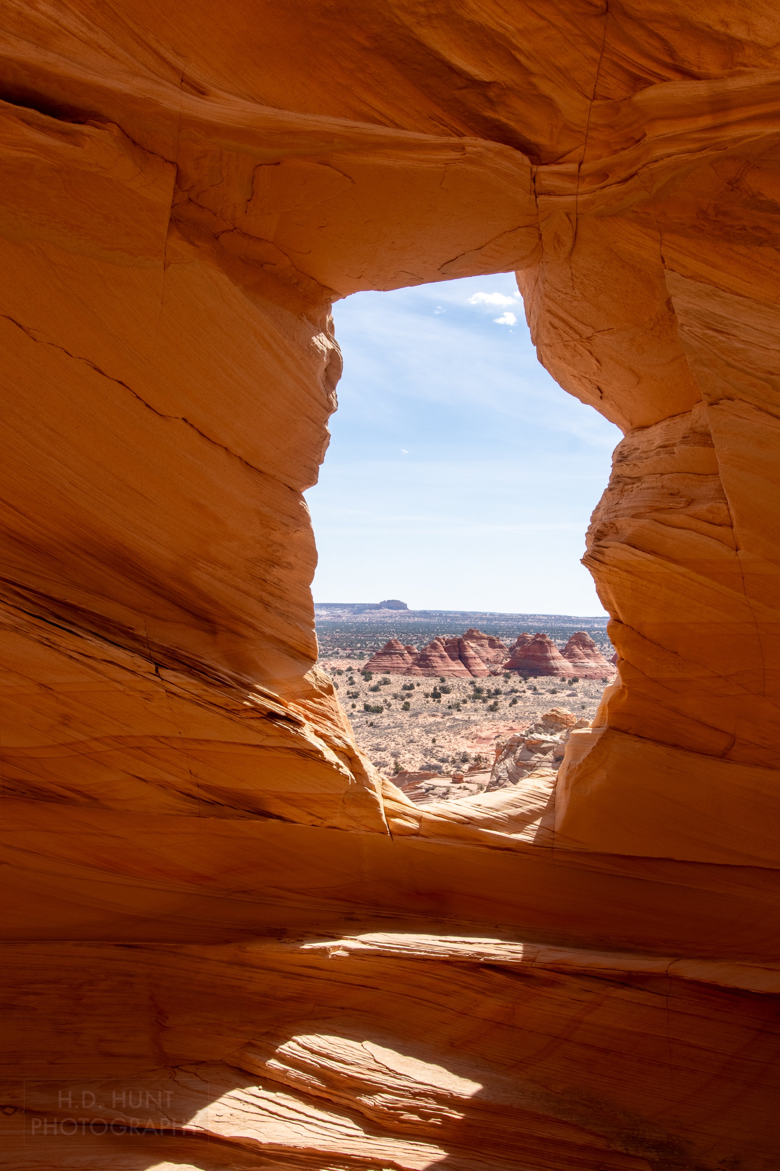 The North Teepees, a red and white sandstone pillar rock formation, is seen through Melody Arch, a gap in a wall of red sandstone cliff, within Coyote Buttes North, Paria Canyon-Vermilion Cliffs Wilderness, Arizona, United States.