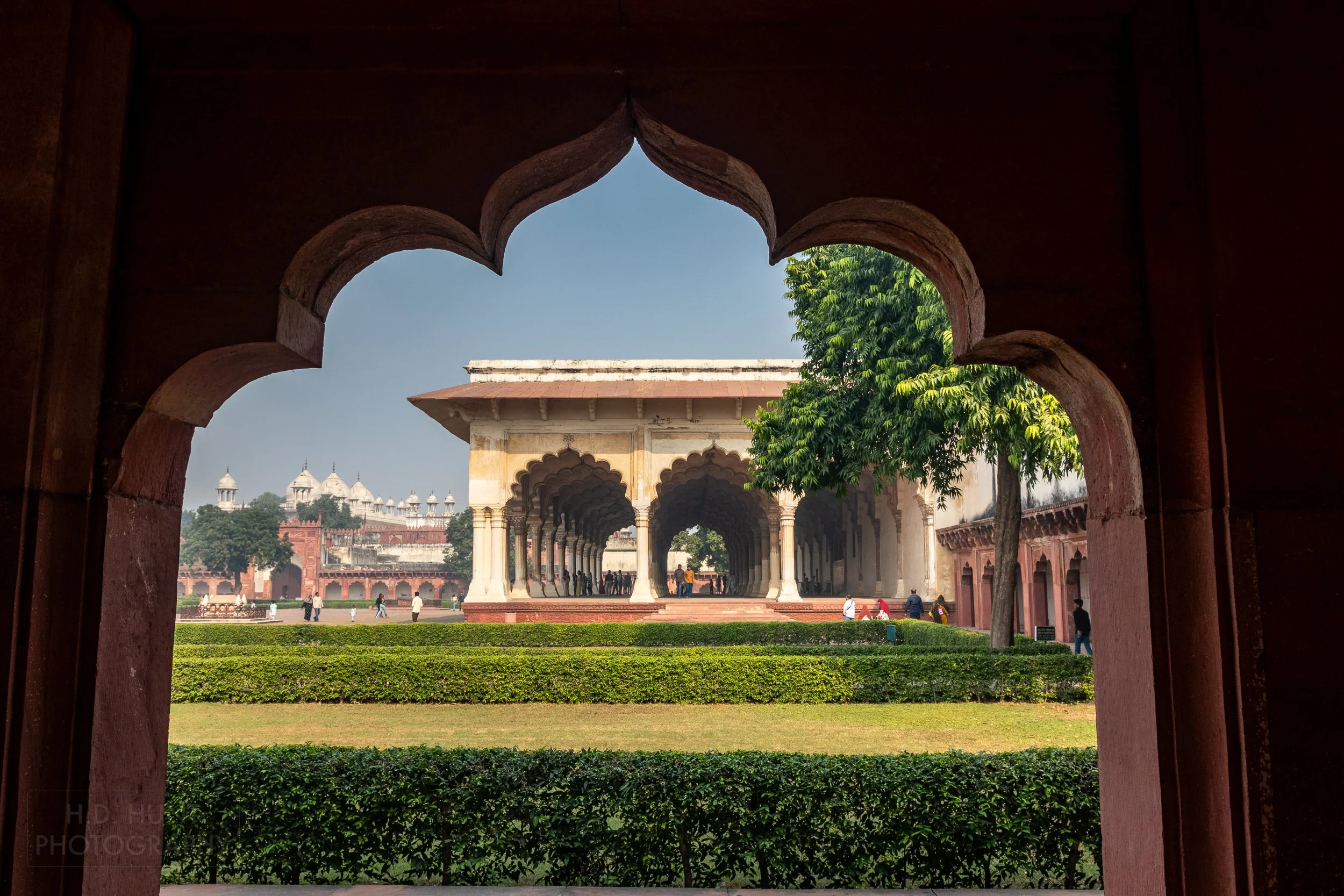 A white colonnade is seen through a red sandstone arch with circular edges, Agra Fort, Agra, India.