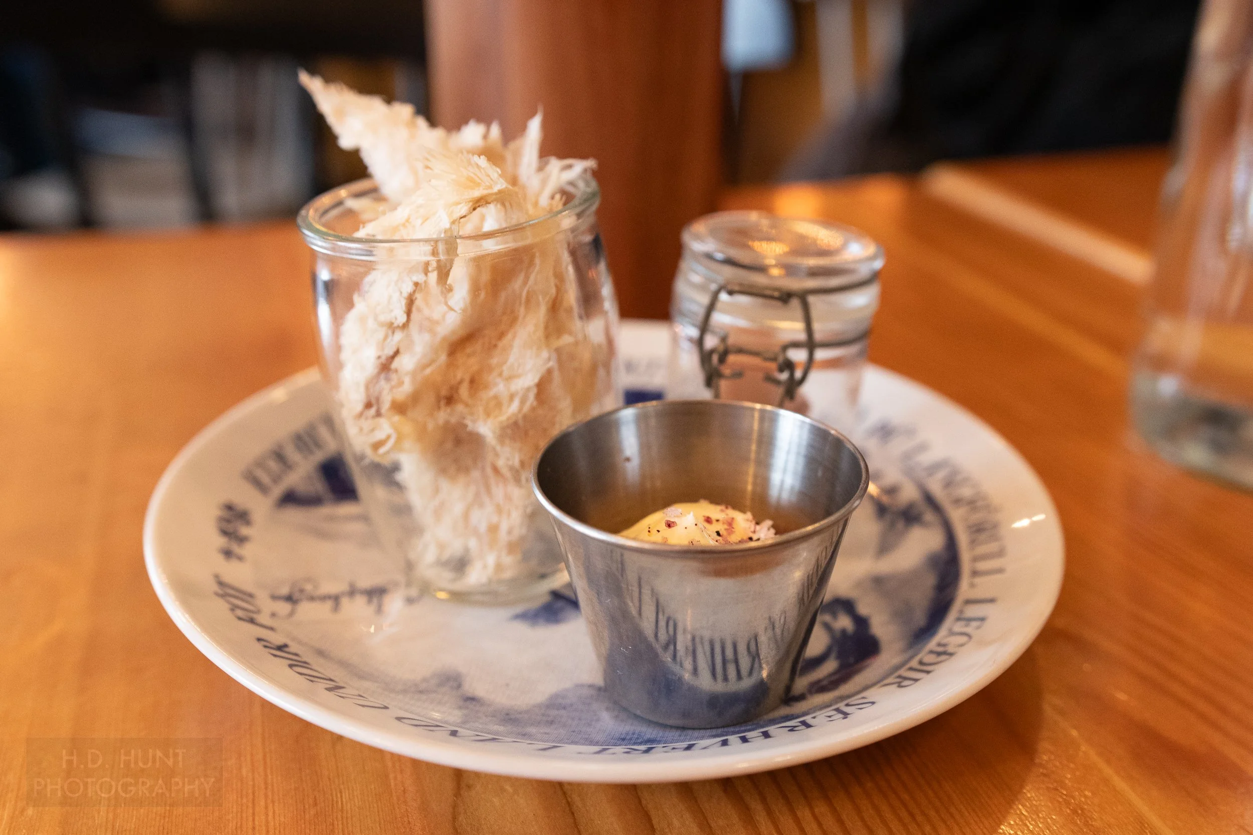 A jar of fermented shark, dried fish, and butter on a plate at Íslenski Barinn, Reykjavík, Iceland.