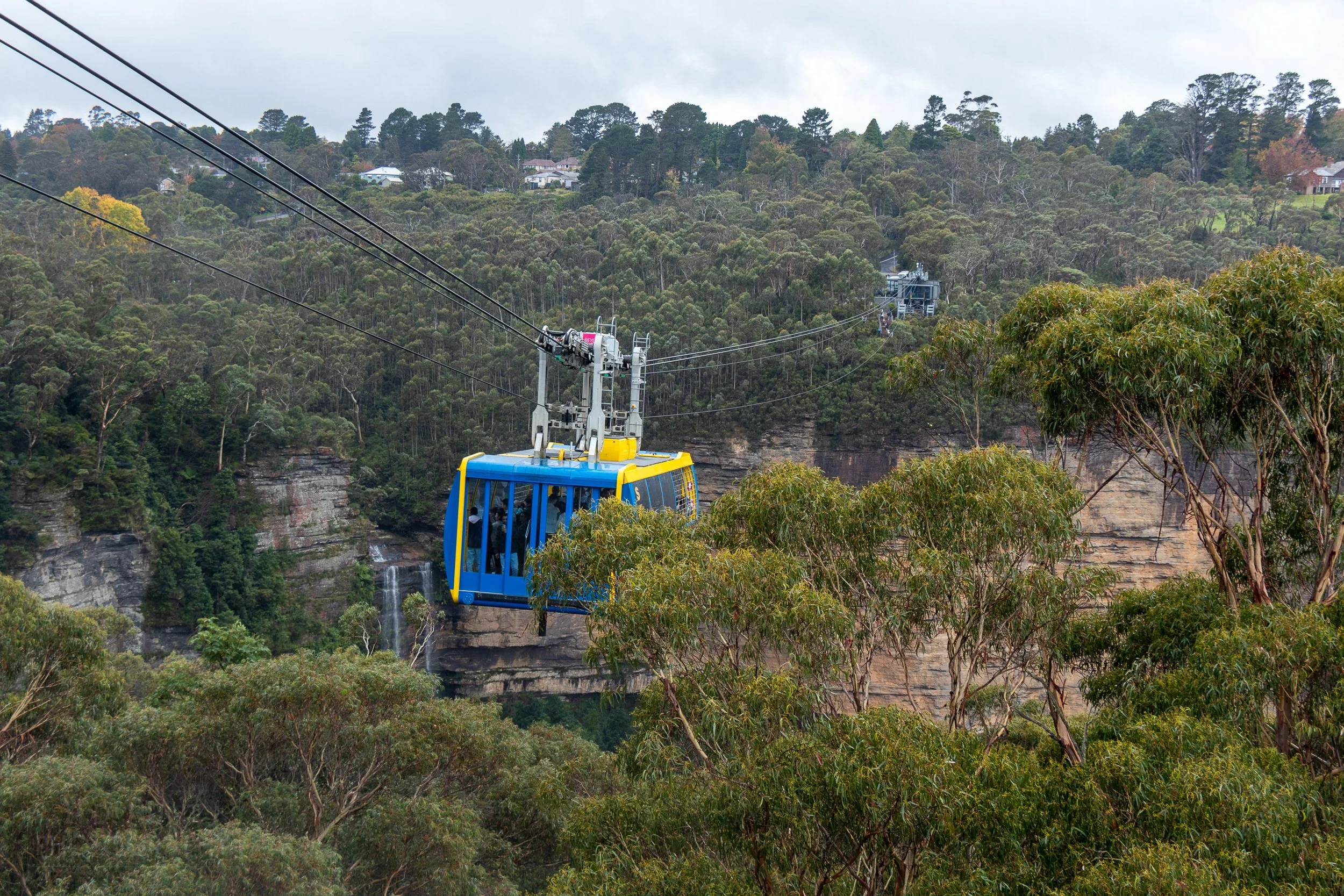 A blue and yellow cable car crosses a small valley at Scenic World, Katoomba, Australia.