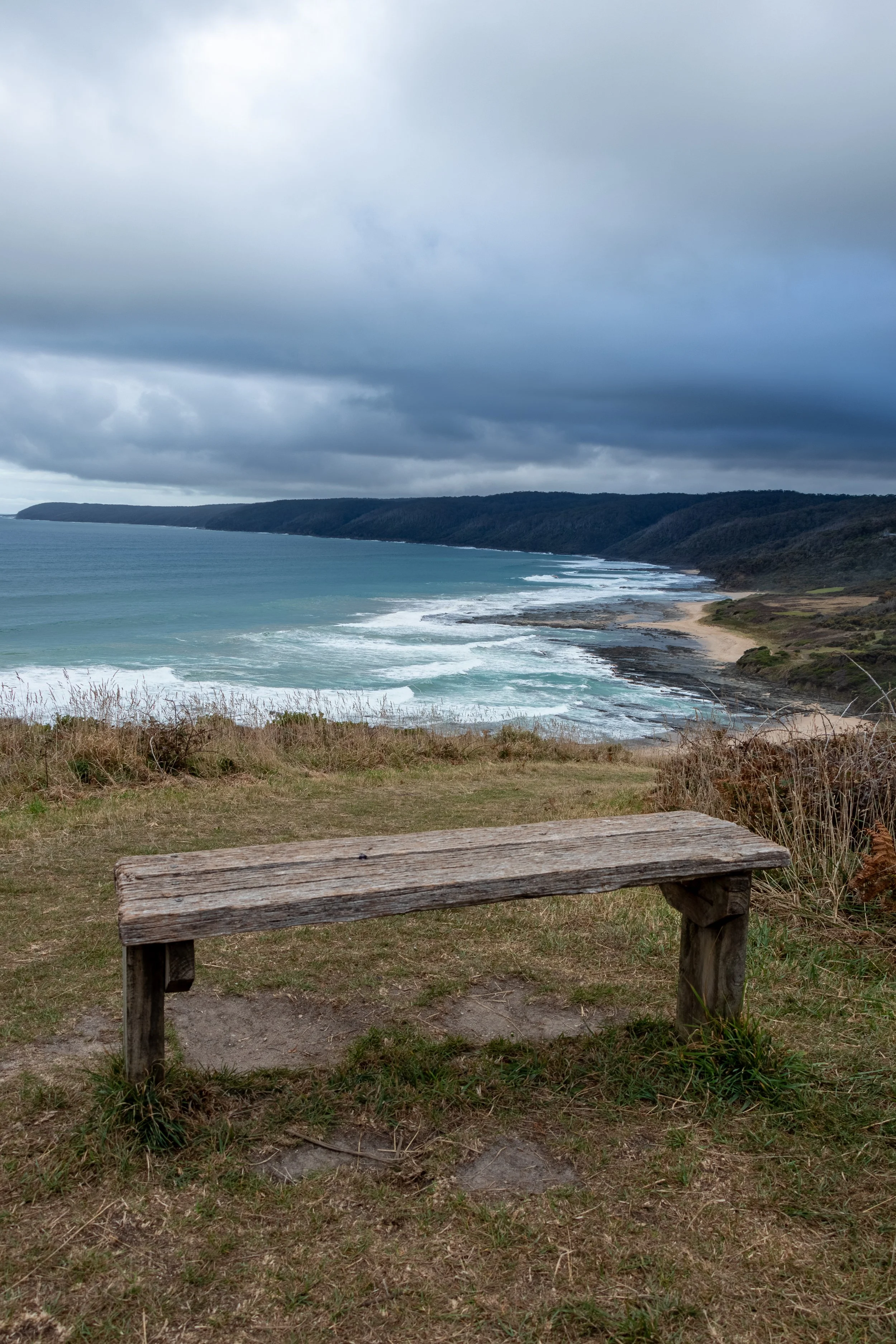 A wooden bench sits on a bluff overlooking the Southern Ocean along The Great Ocean Walk, Victoria, Australia.