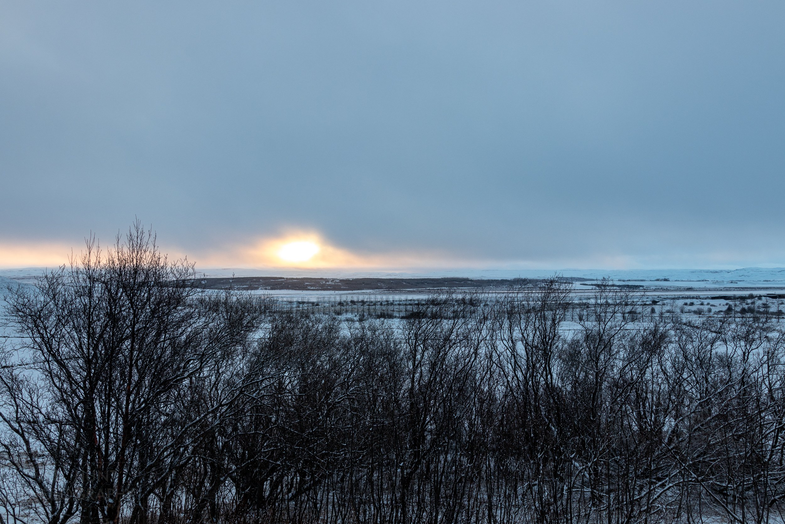 Sunrise pieces grey clouds over the village of Reykholt, Iceland.