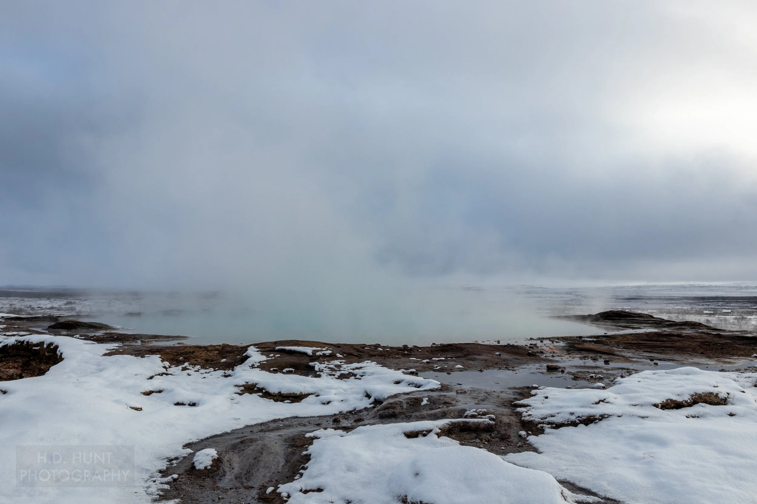 Steam rises from a geothermal vent in the ground at Haukadalur, Iceland.