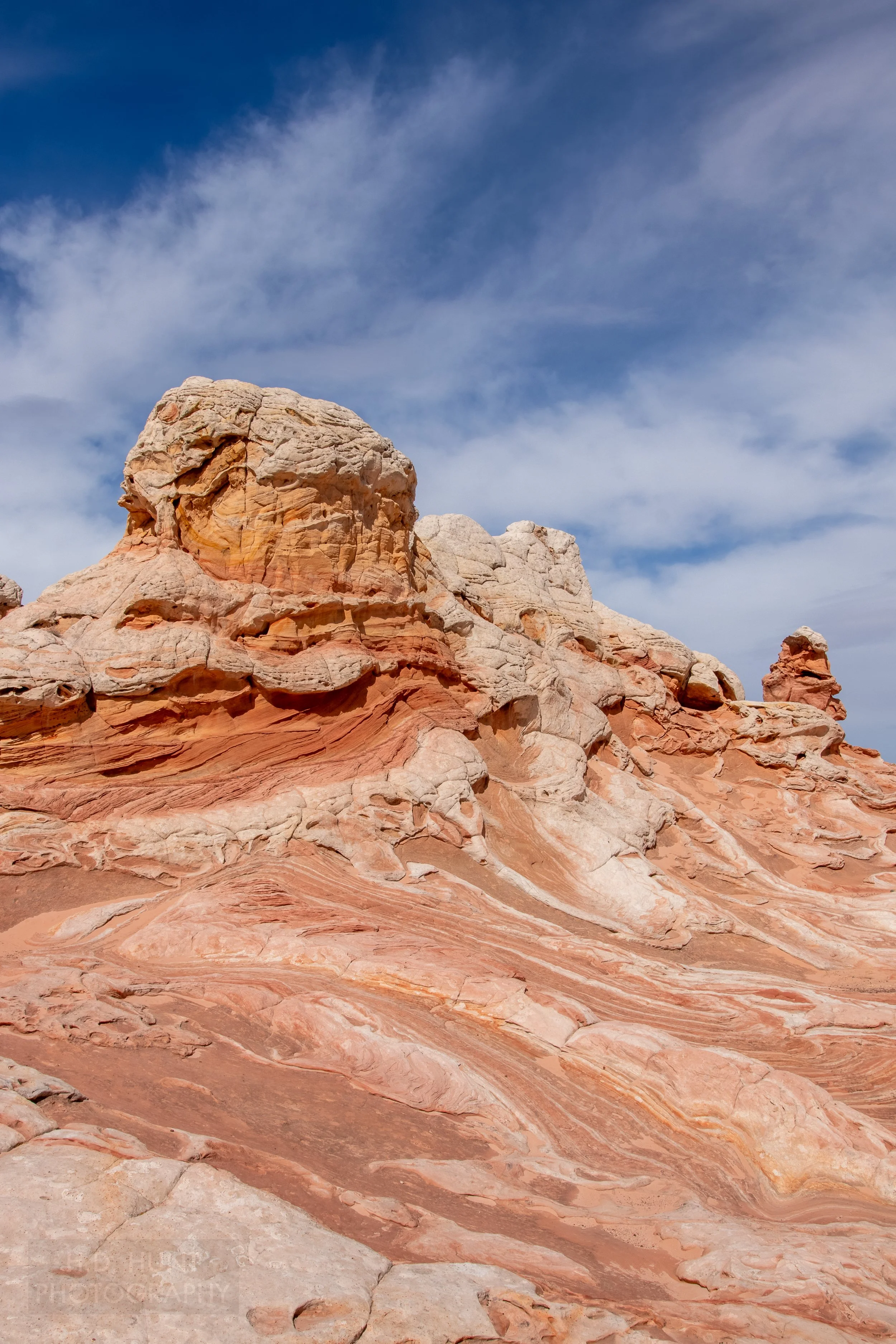 Large columns of white rock rise above deformed red and white striped bedrock in White Pocket, Vermillion Cliffs National Monument, Arizona, United States.