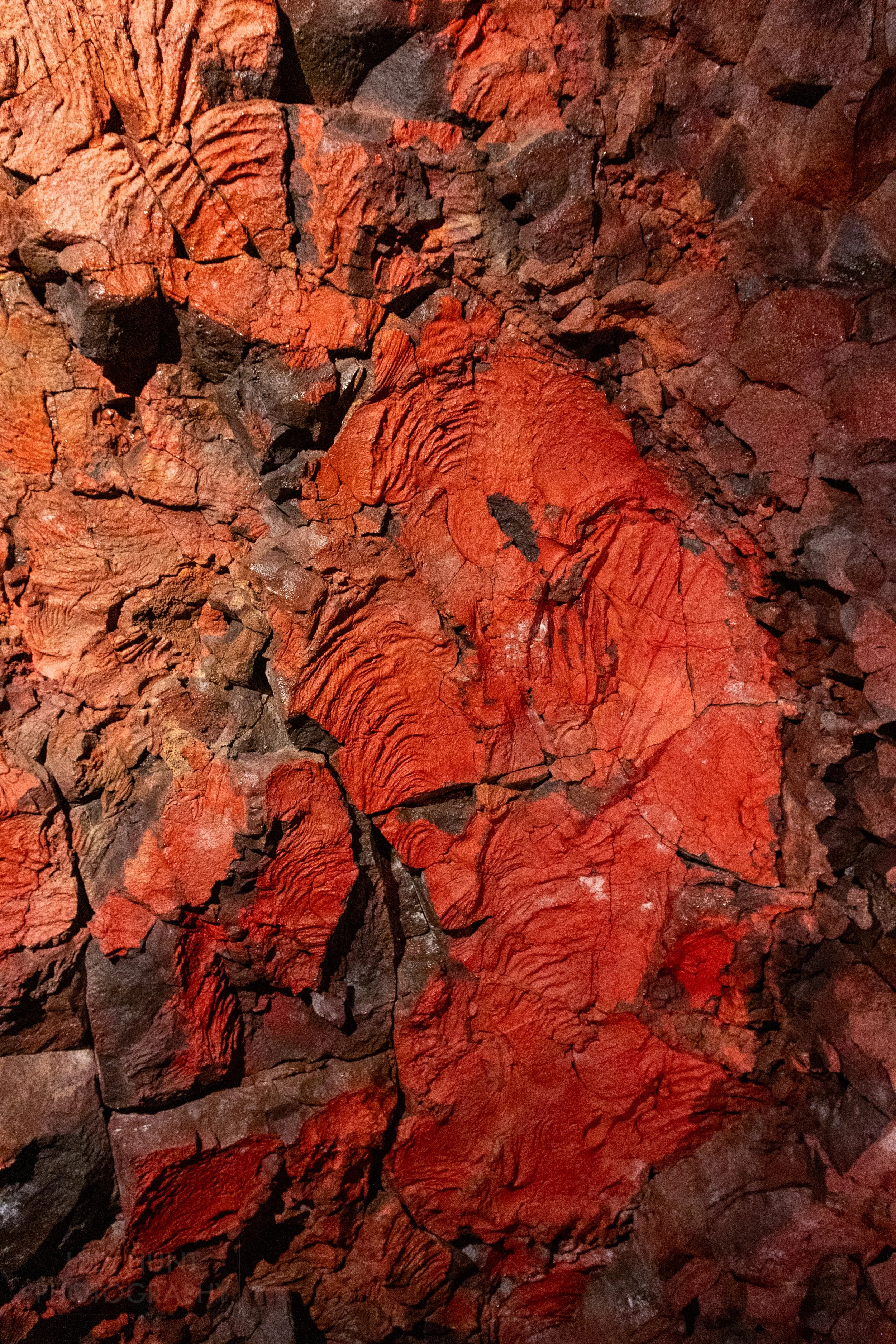 Deep red coloration is seen on a black stone wall within the lava tube Raufarhólshellir, Iceland.