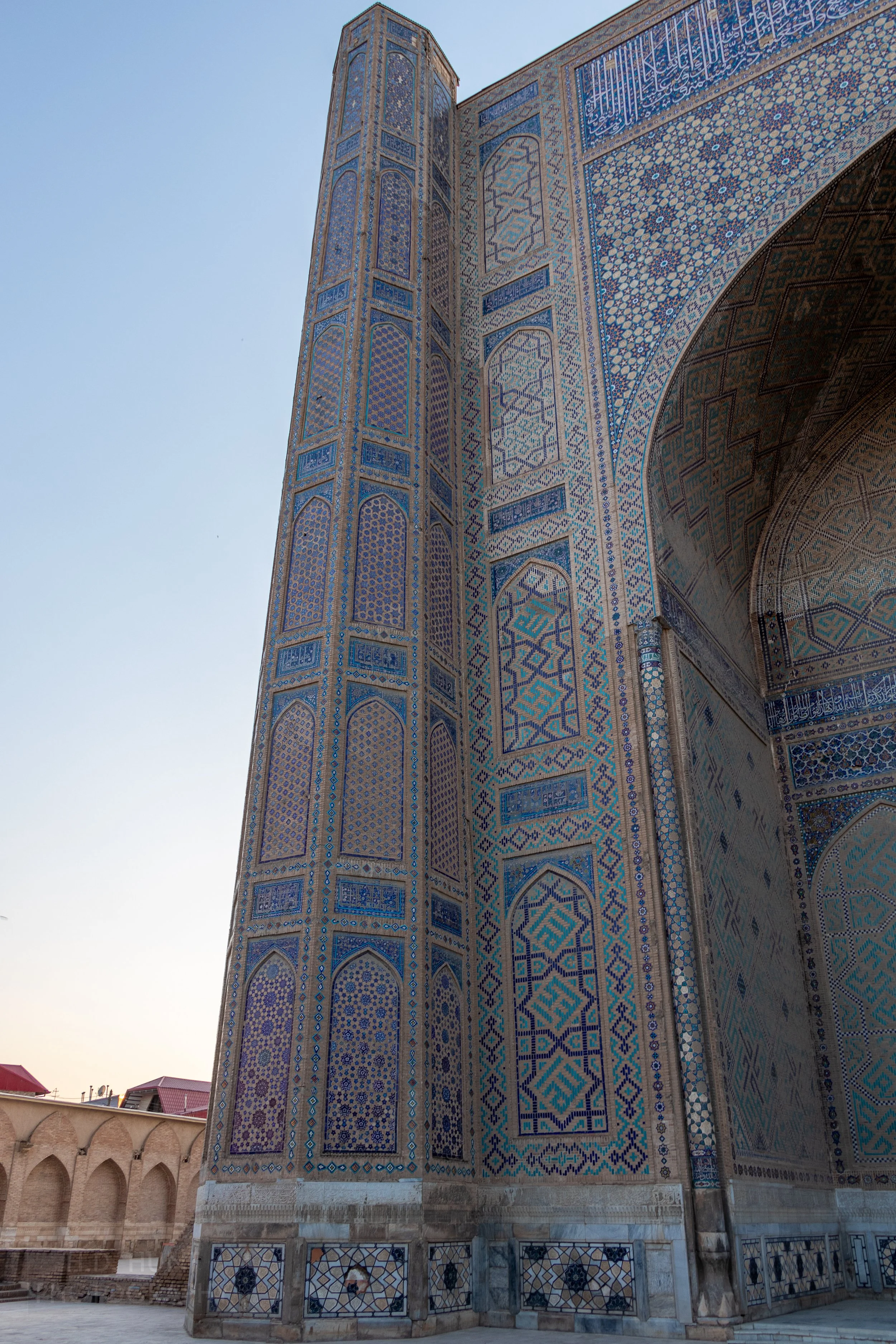 Ornate light blue, dark blue, and tan tiles on the exterior of a structure at the Bibi-Khanym Mosque, Samarkand, Uzbekistan.