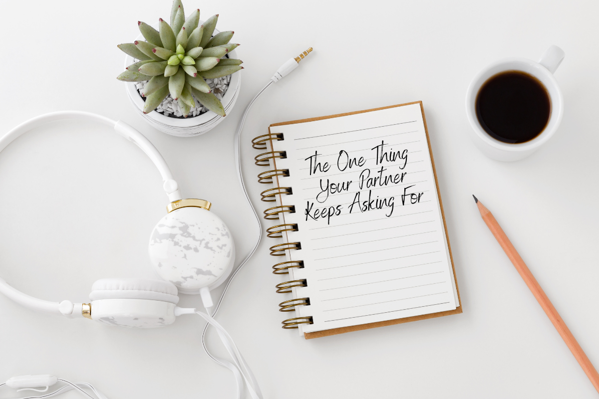 An open notebook with the words "The One Thing Your Partner Keeps Asking For," placed beside a coffee cup, pencil, headphones, and succulent plant, symbolizing relationship advice and reflection.