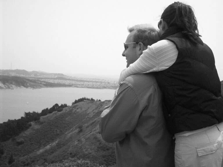 A couple embracing while looking out over the water, symbolizing reflection and connection in marriage.