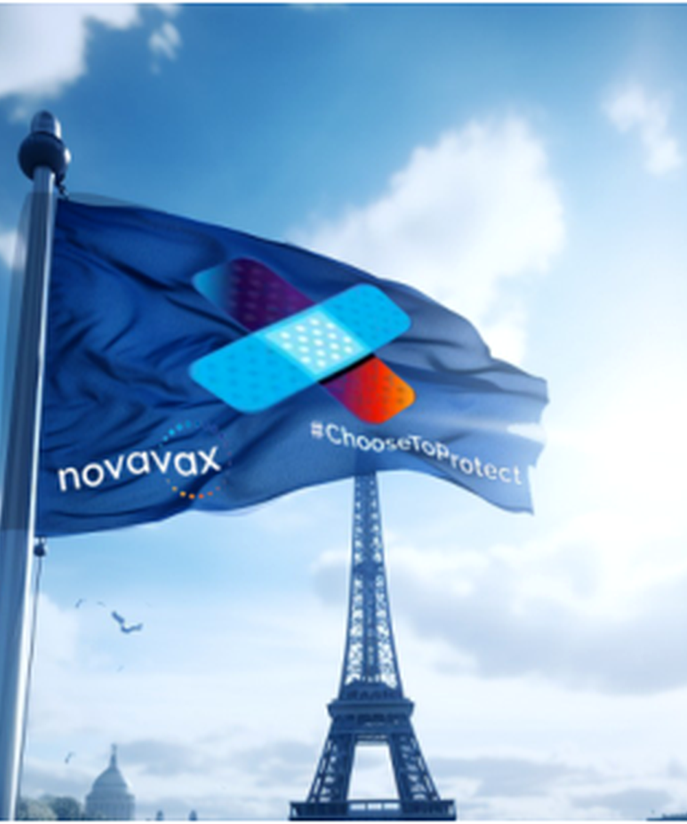 A flag with the Novavax logo, hashtag #ChooseToProtect, and a colorful abstract design, flying in front of the Eiffel Tower with the Paris skyline and a partly cloudy sky in the background.