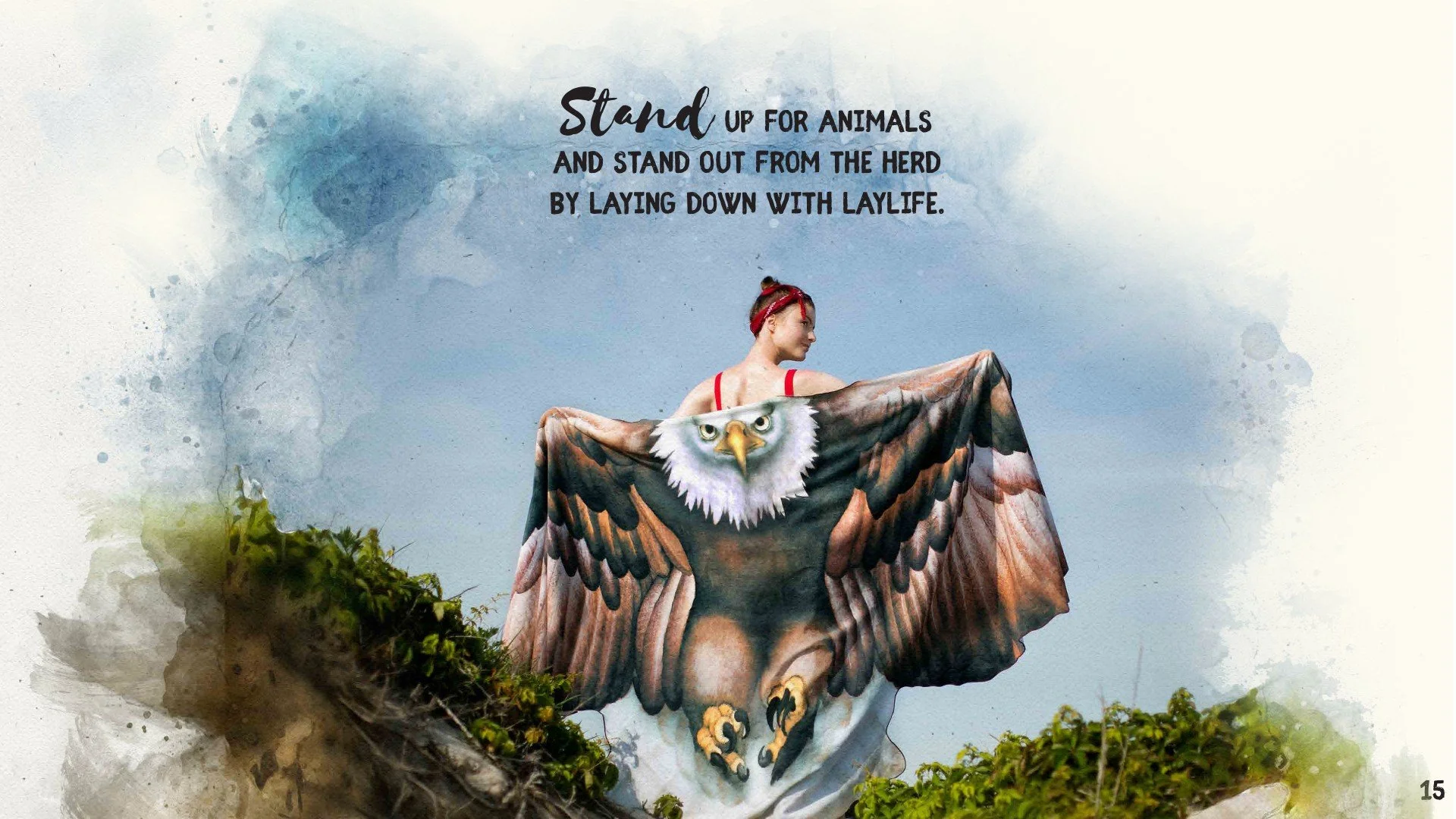 A woman standing outdoors holding a large eagle-shaped fabric with outstretched wings and an eagle's face, with clear sky and some greenery in the background.