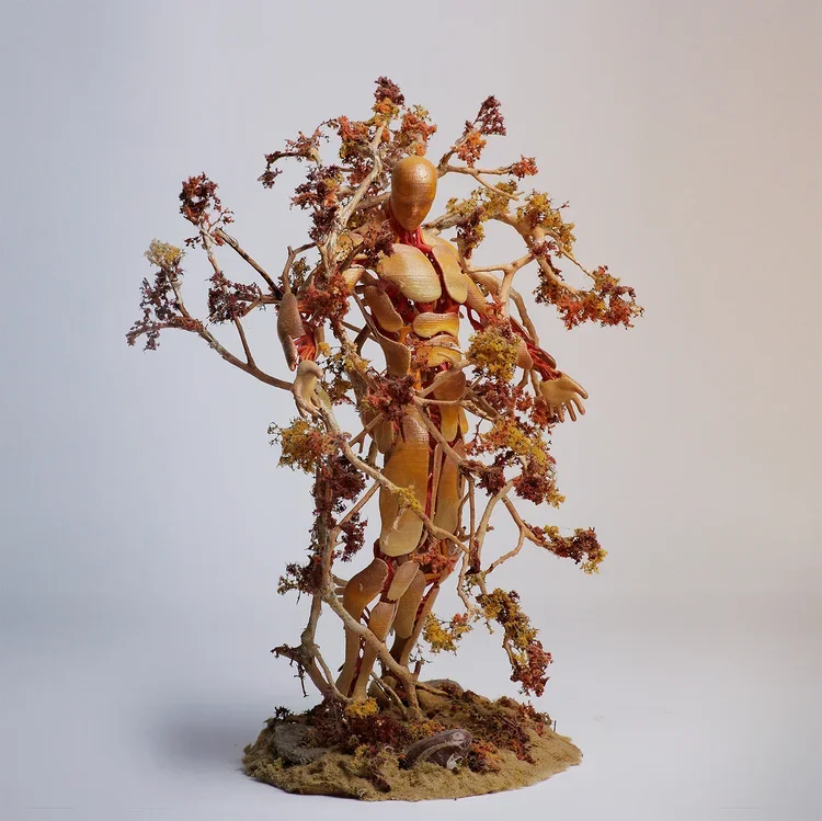 A wooden artist mannequin intertwined with dried flowering plant branches, standing on a textured base.