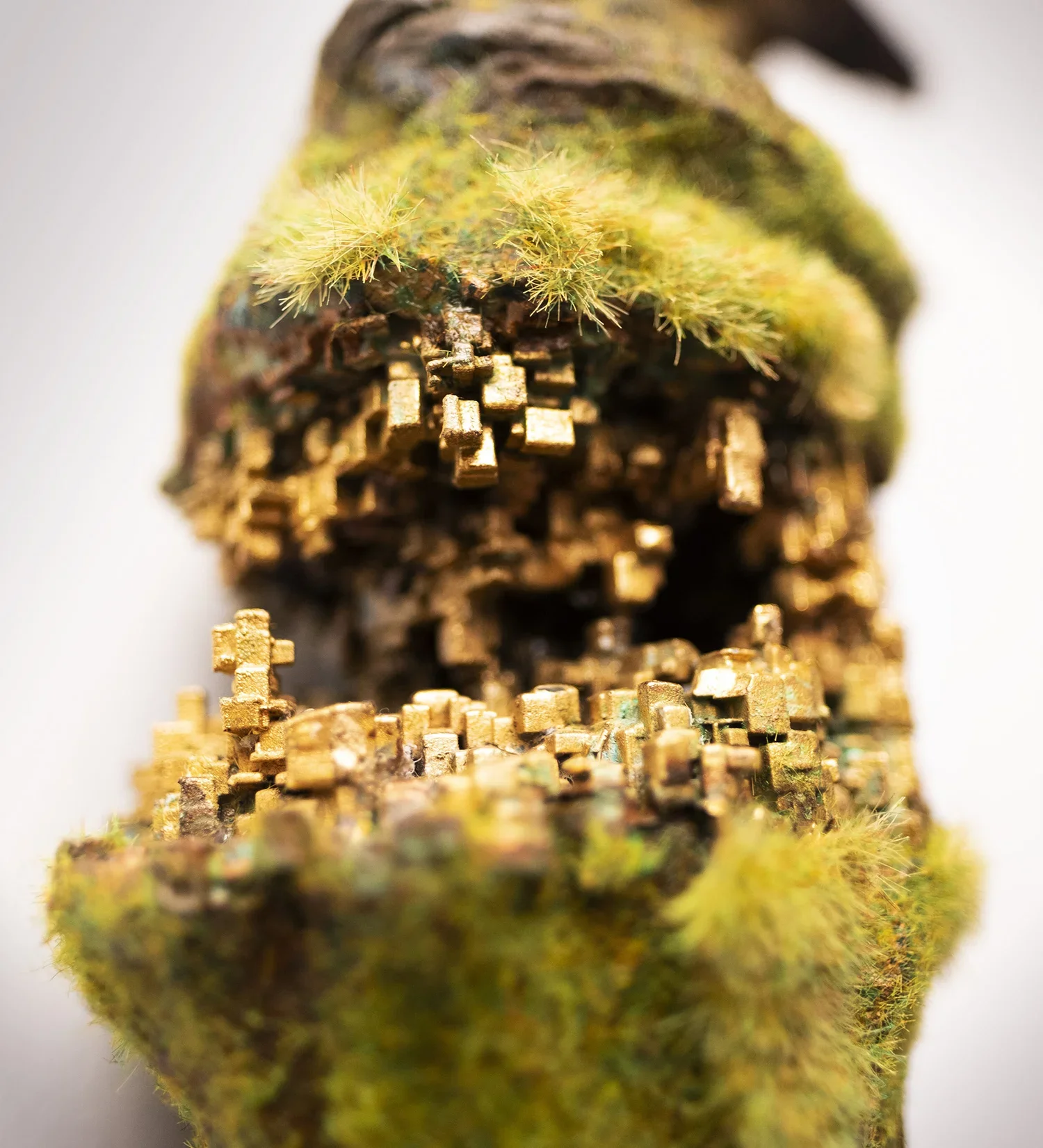 Close-up of a moss-covered, miniature, fantasy-style structure built from small interconnected blocks with a hollow interior, resembling a tiny tower or dwelling.