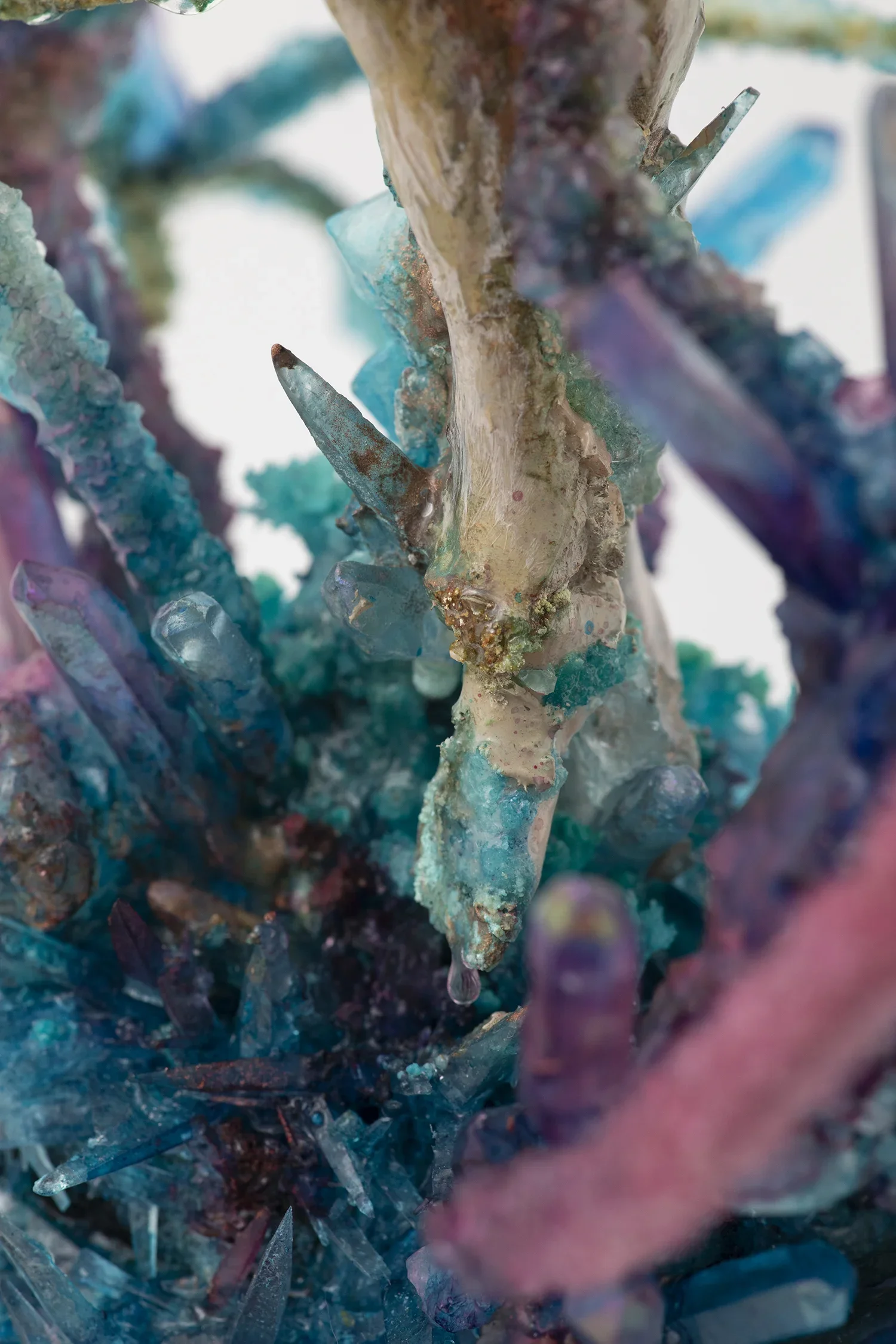 Close-up of a sculpture made from colorful, textured materials, featuring turquoise, purple, and beige tones, with jagged, crystalline protrusions.