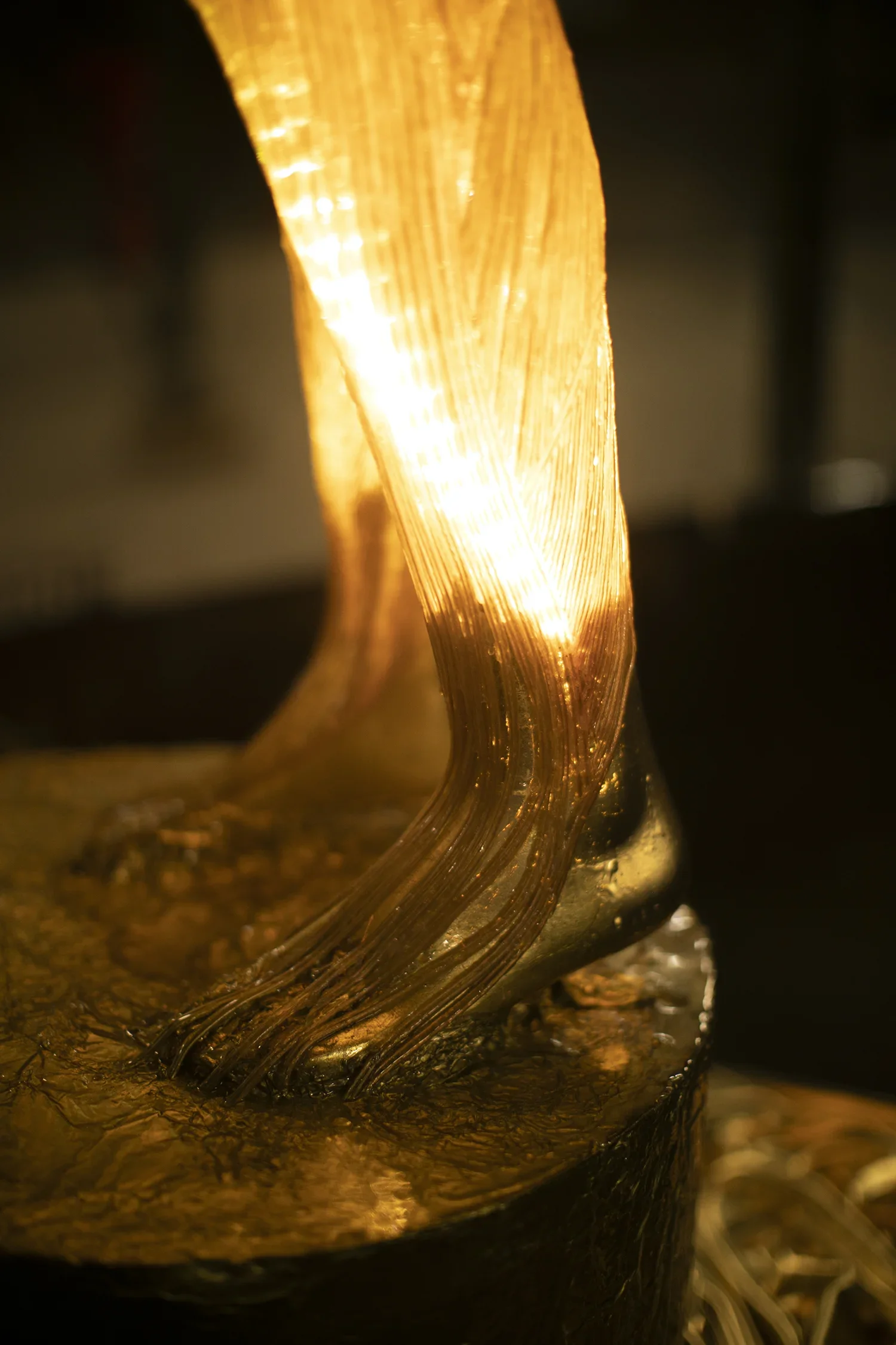 Close-up of a decorative gold sculpture with flowing, textured design and lighting that highlights its curves and metallic surface.