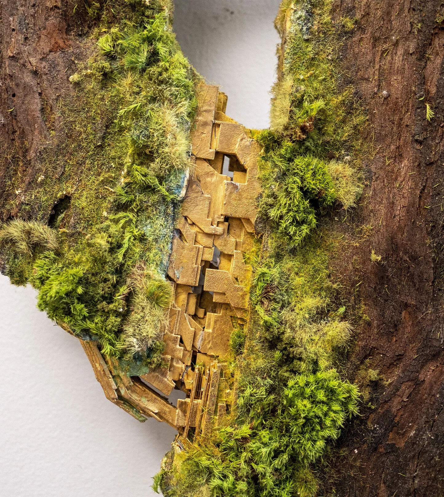 Miniature model of a forest scene with lush green moss and a small wooden structure on a textured, earthy base.