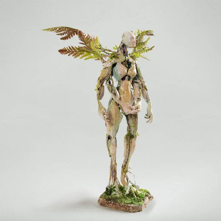 Statue of a humanoid figure with plant-like features and foliage on its head, standing on a mossy base.