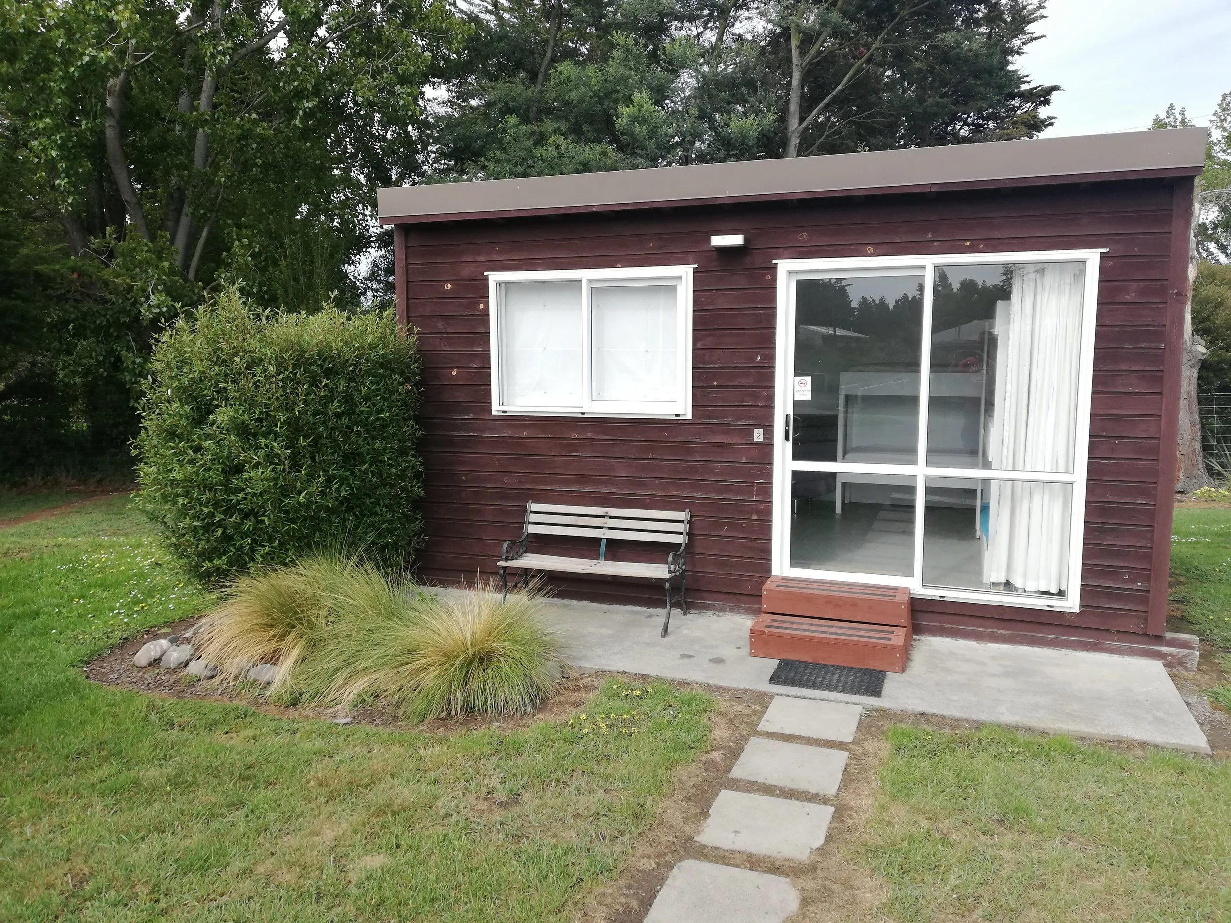 A small cabin with a fully made queen bed and one set of single bunk beds. Similar kitout to our family cabins, but no running water.