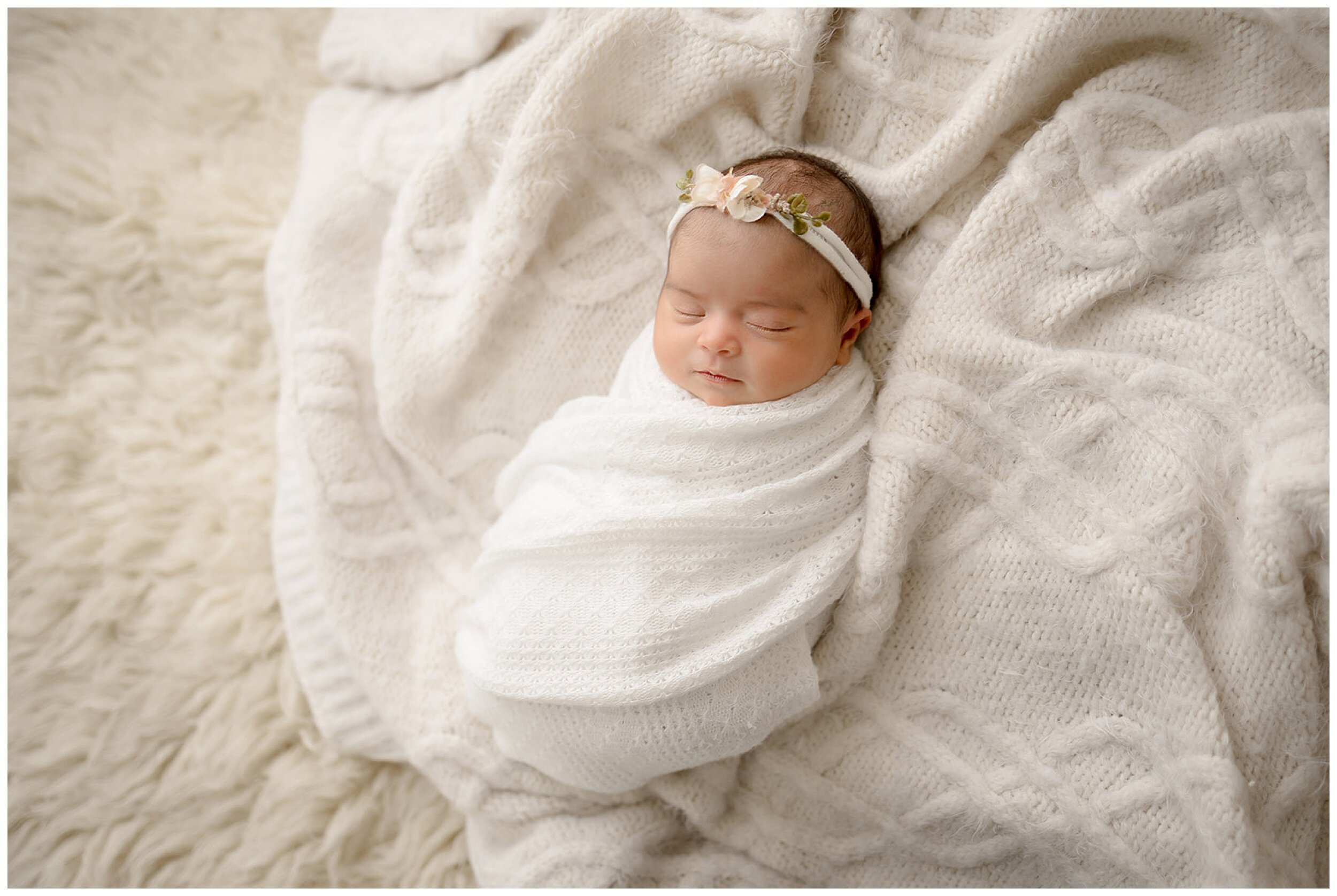 newborn laying in white blanket